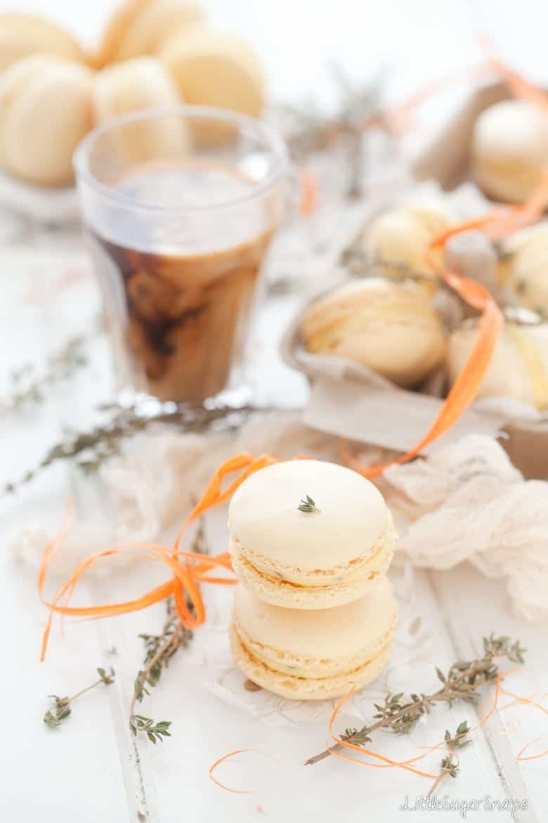 Two orange thyme macarons with a cup of coffee.