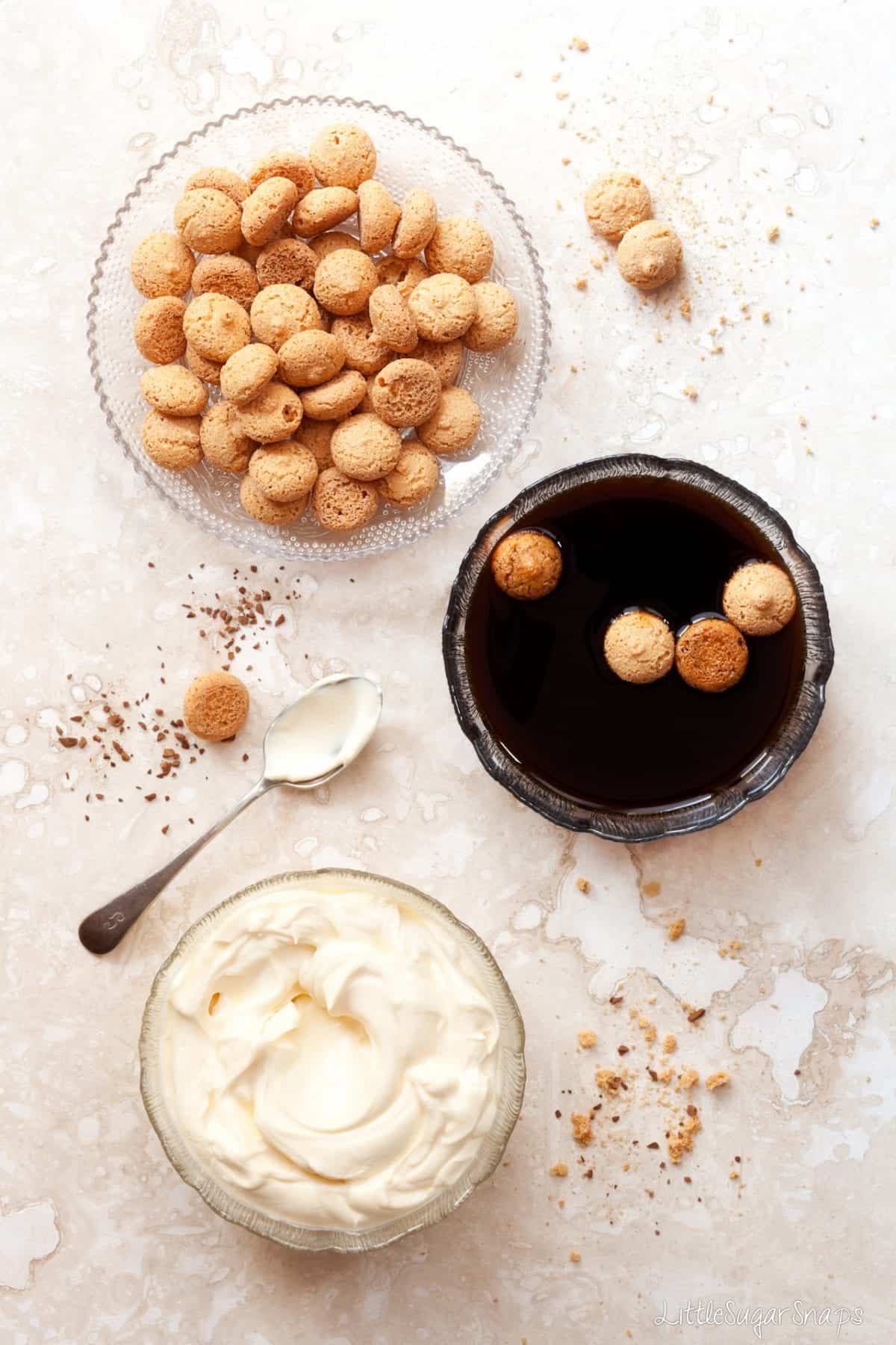 Amaretti cookies being dipped in a bowl of coffee for Tiramisu.