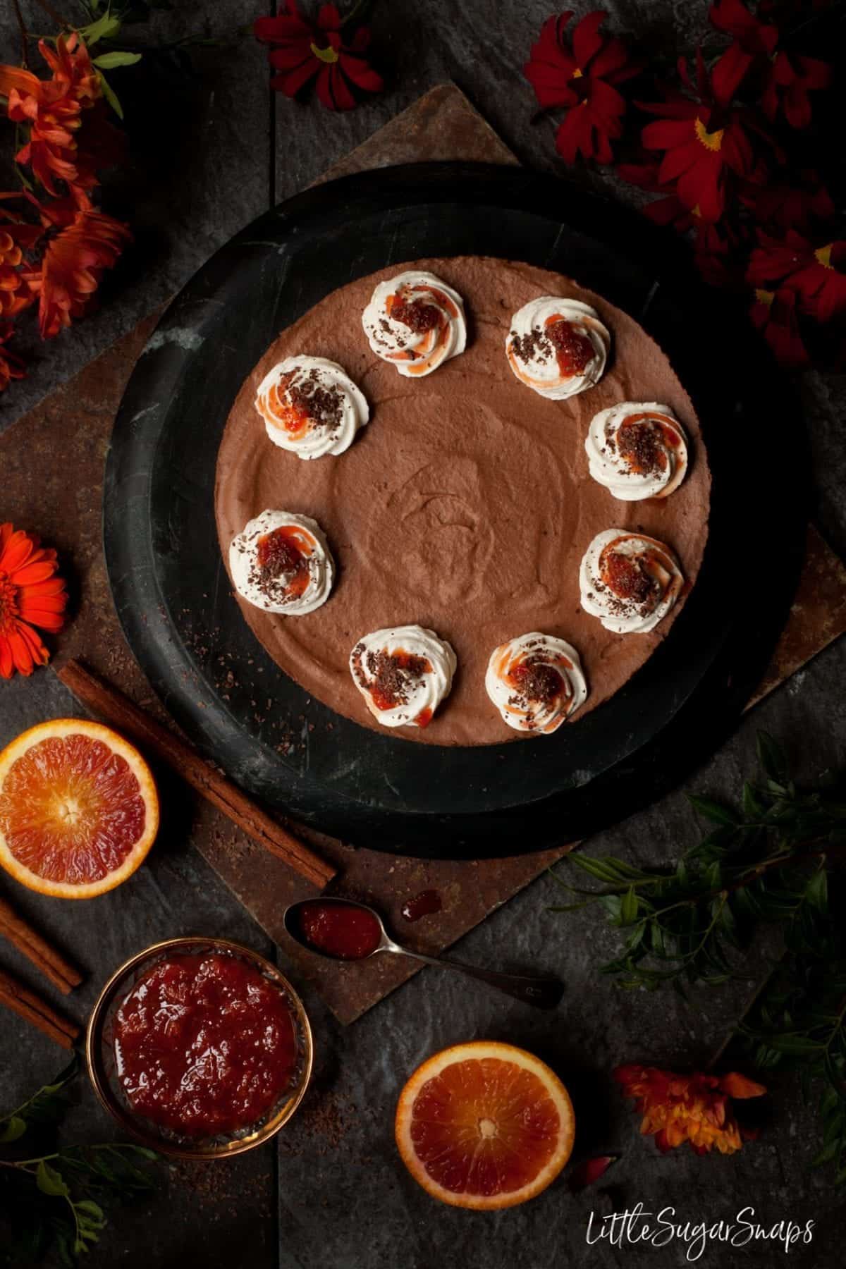 Overhead view of chocolate mousse cake with a bowl of blood orange compote alongside.