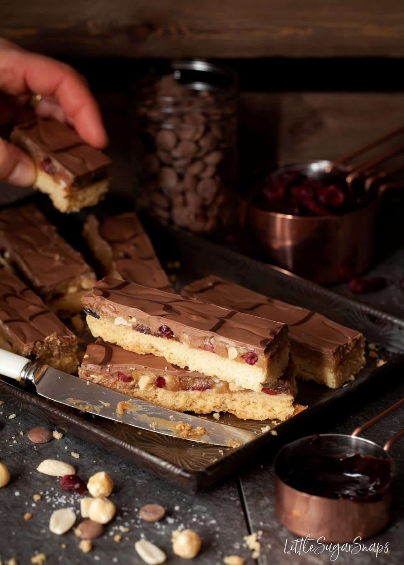 Person taking a slice of millionaire's shortbread bars from a vintage baking tray. 