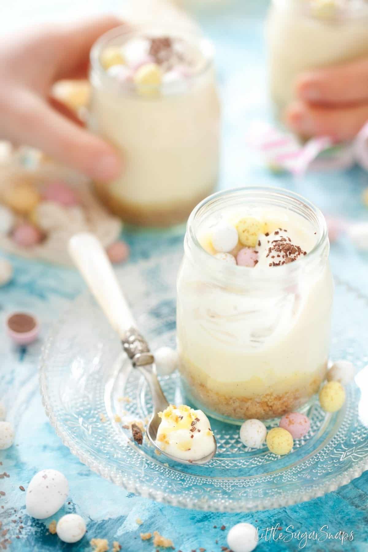 White chocolate desserts in glass pots. One is part eaten and children are taking others away
