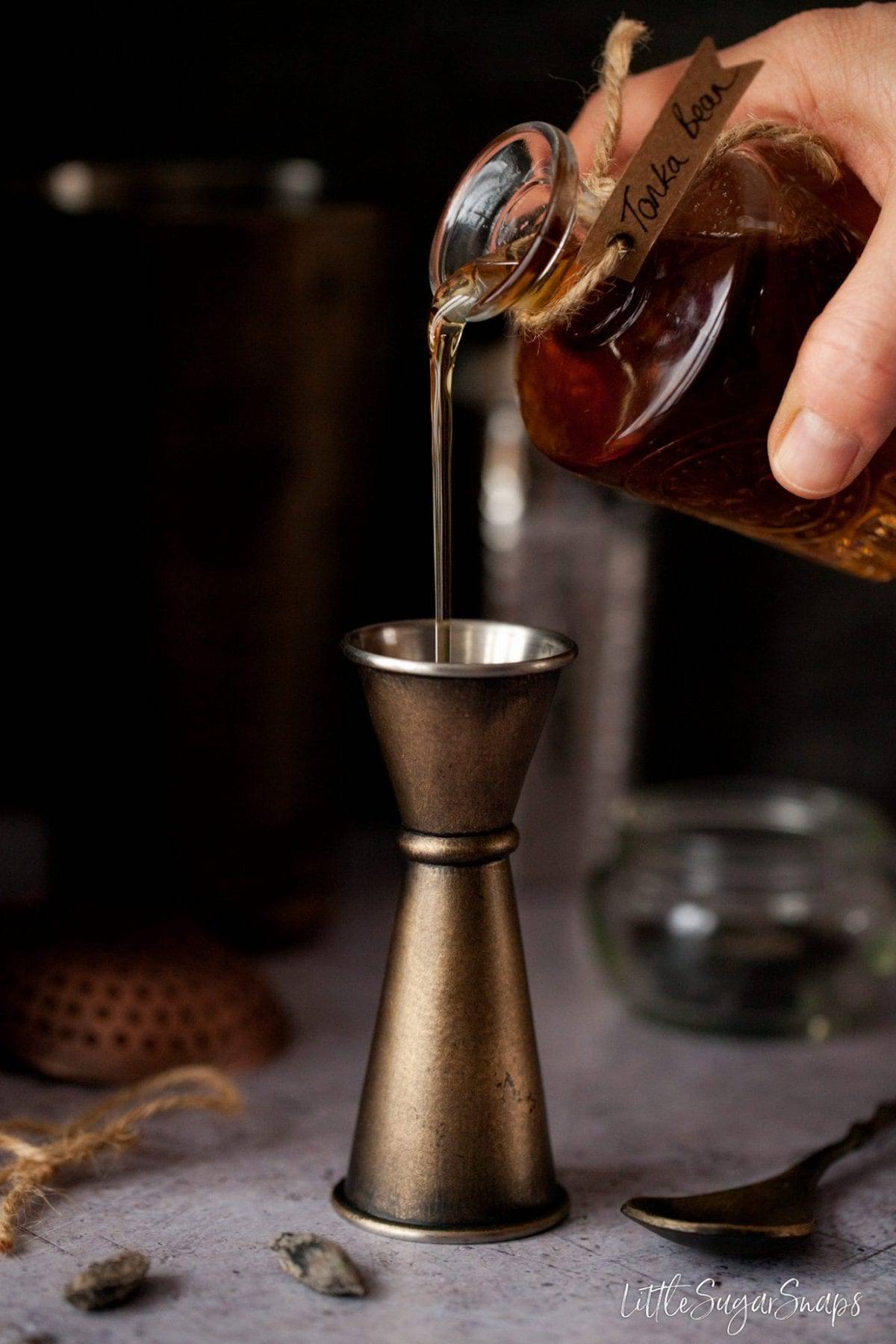 Tonka Bean Syrup being poured into a cocktail jigger.