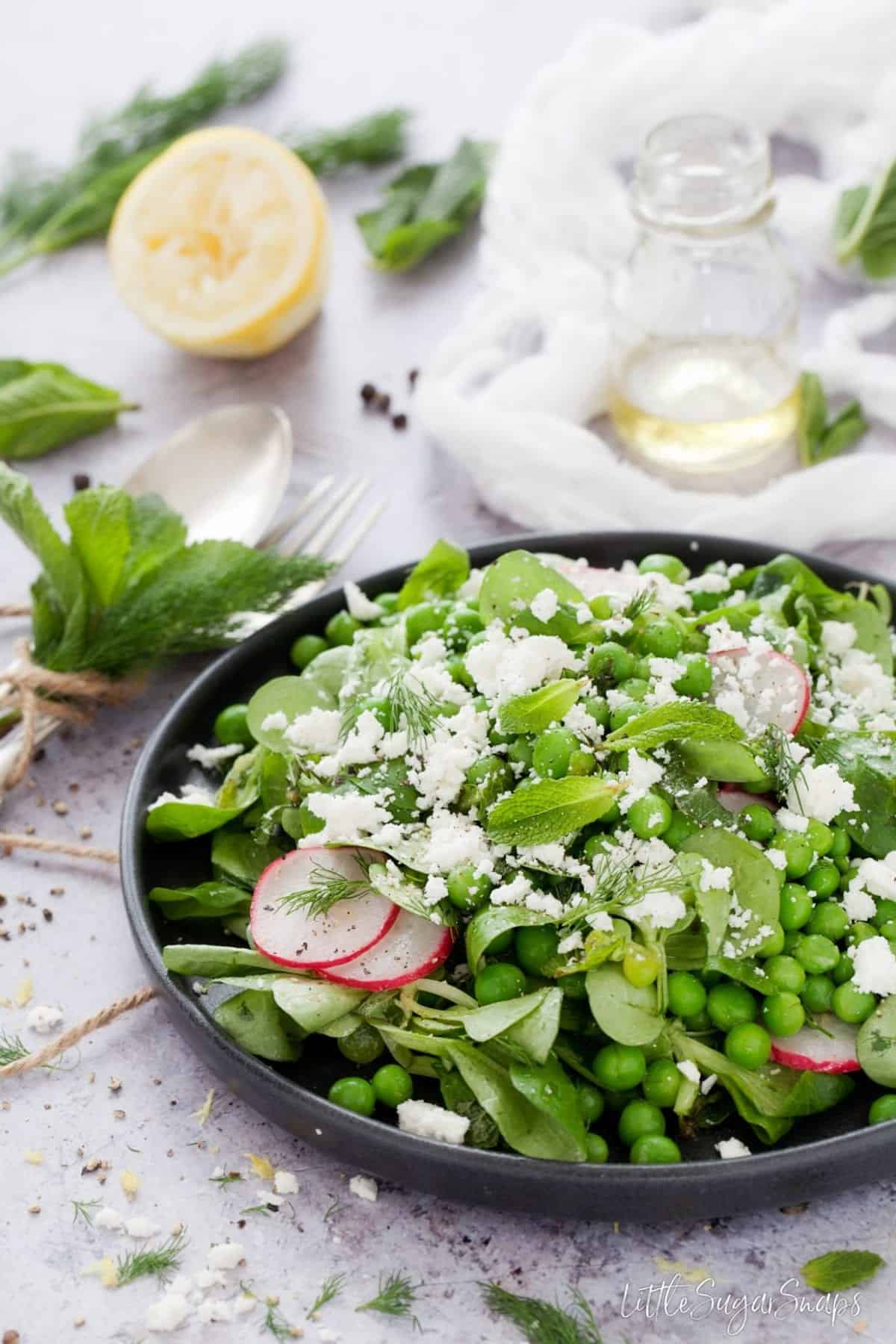 A plate of mint and pea salad with goats cheese on top.