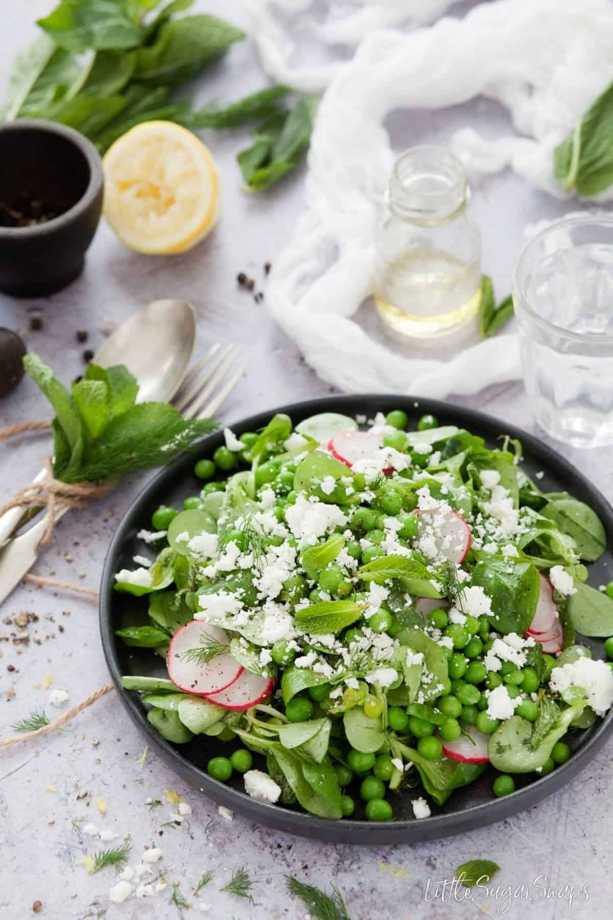 A plate of mint and pea salad with feta cheese and pink radish slices.