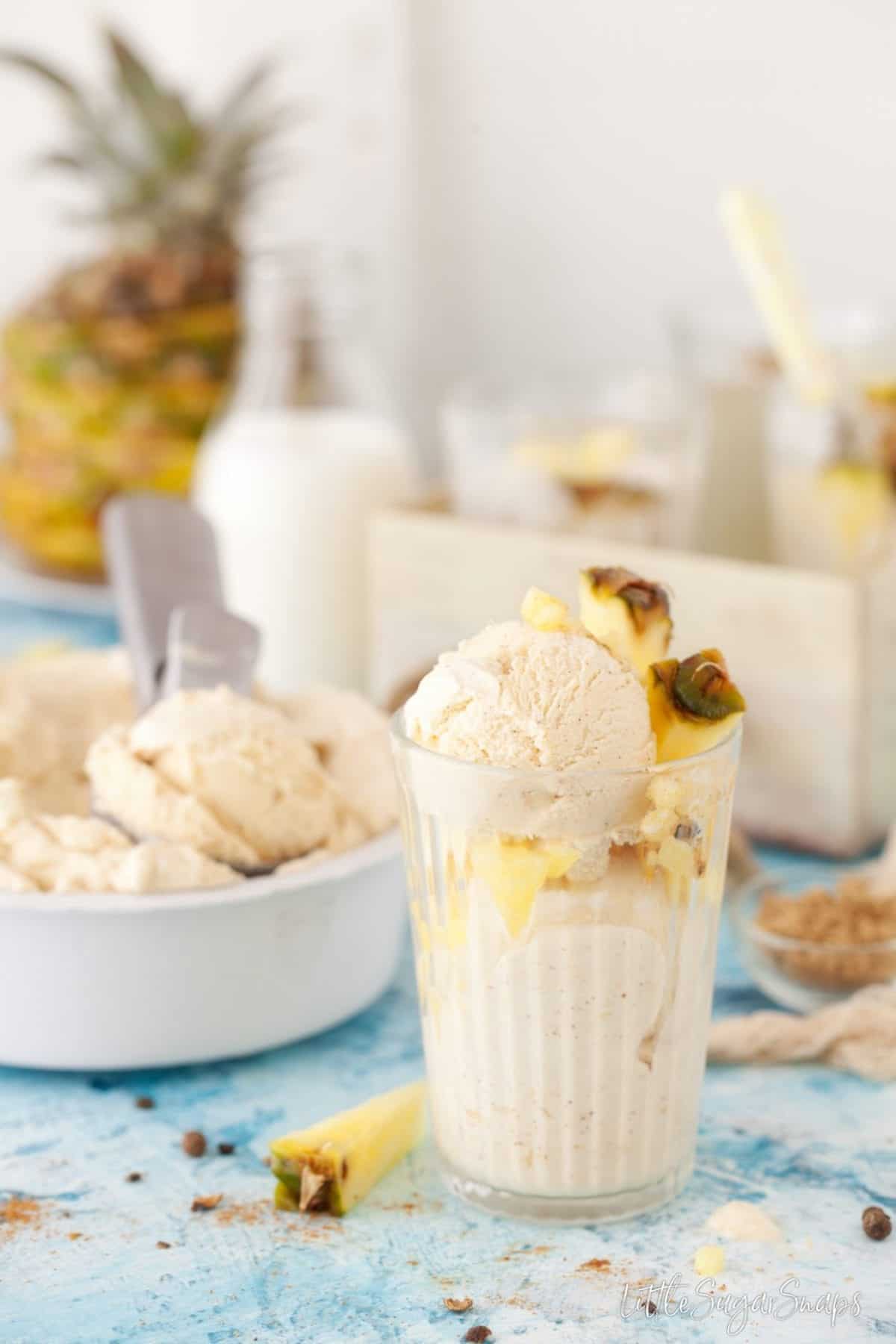 A glass with scoops of ice cream and fresh pineapple.