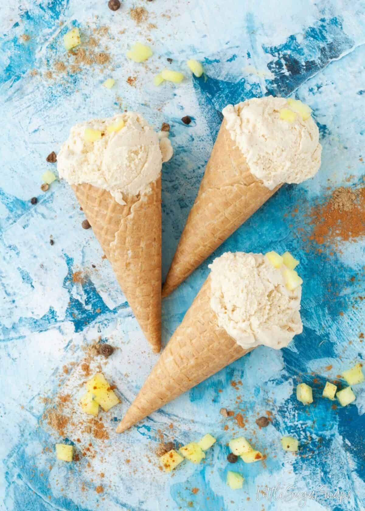 Roasted Pineapple Ice Cream in waffle cones against a blue background.