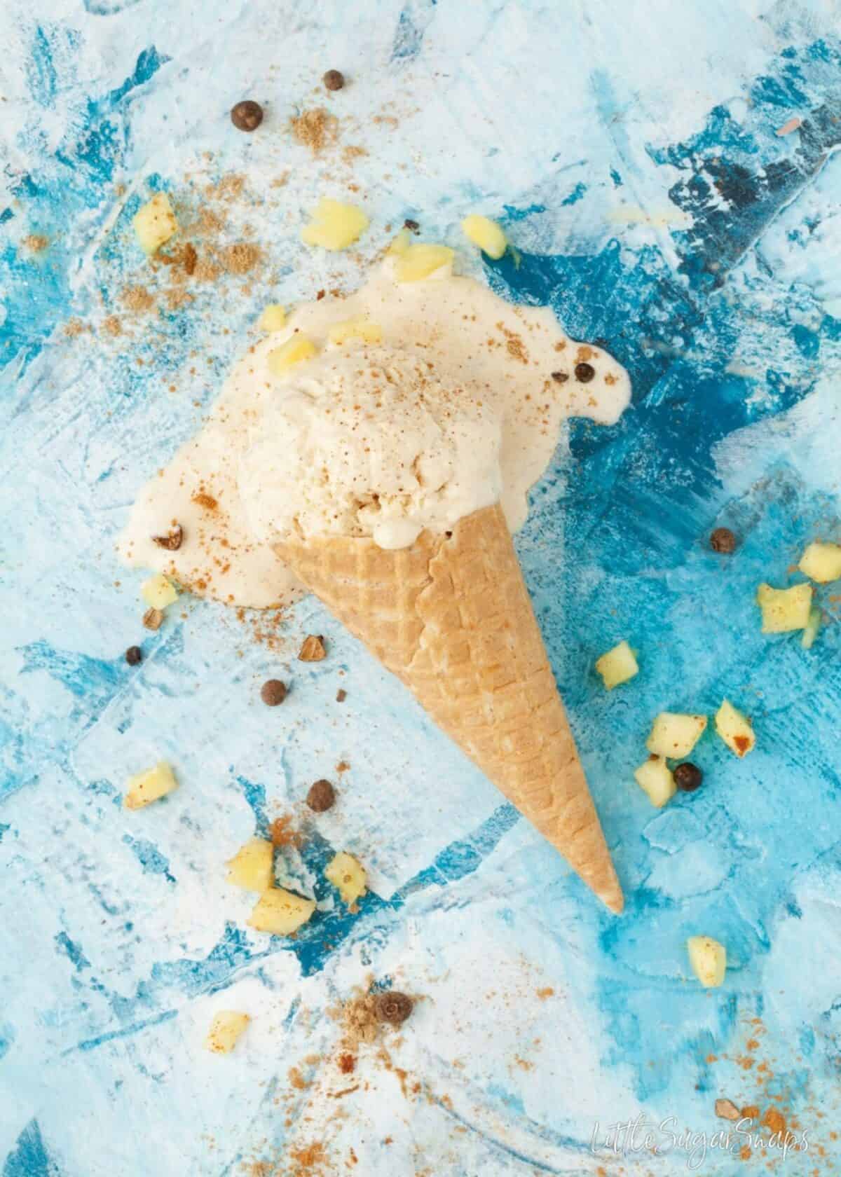 Overhead view of a waffle cone with melting pineapple ice cream in it.