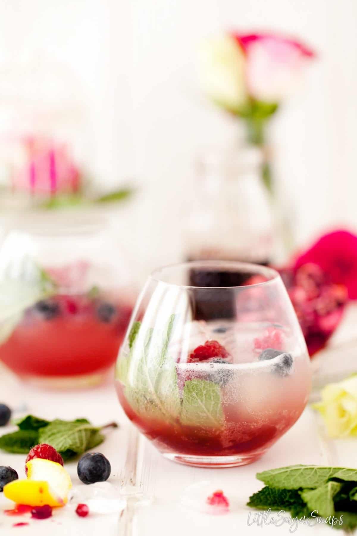 A fruity drink made with grenadine and garnished with mint and berries.