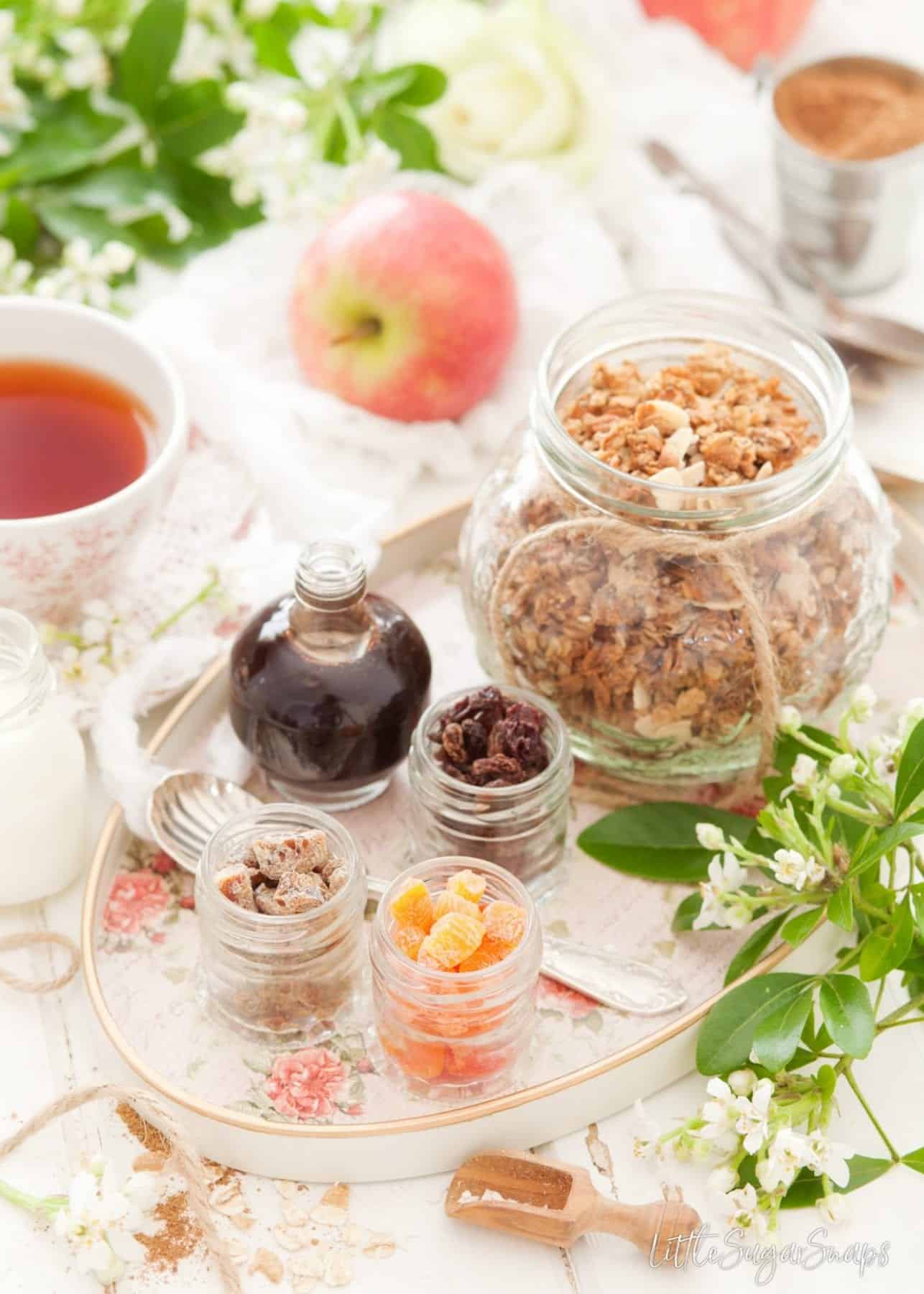 A jar of granola with small pots of dried fruits.