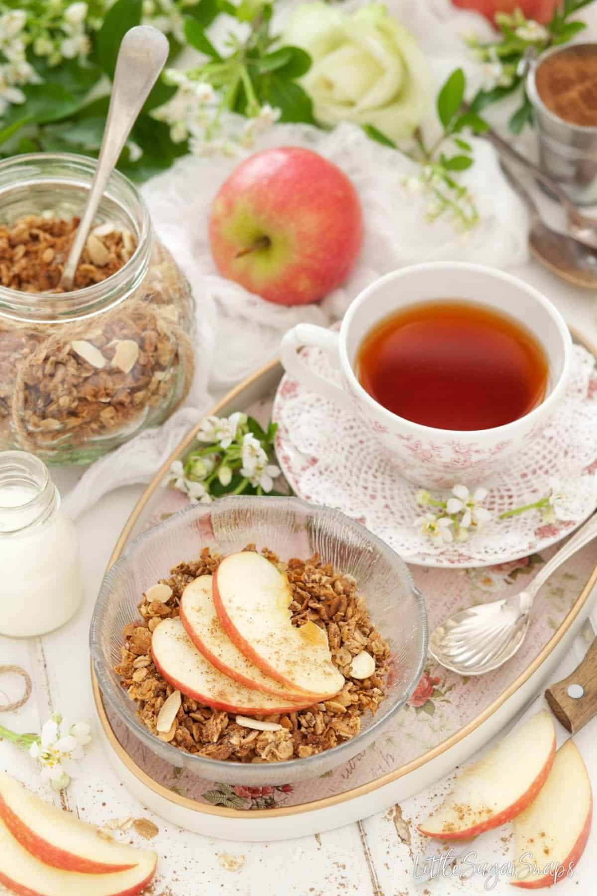 Spiced Apple Granola with fresh apple slices and a cup of tea.