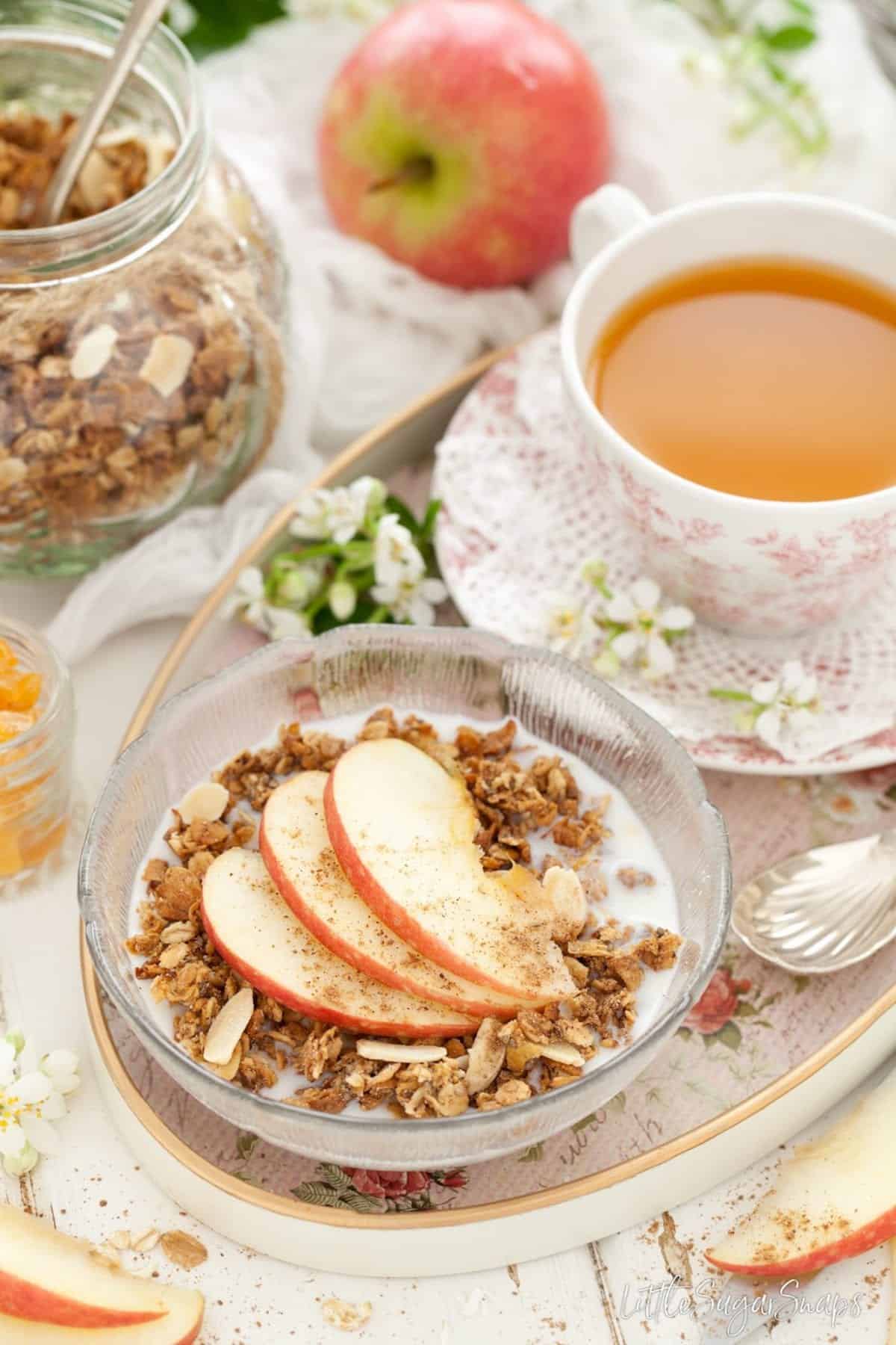 Spiced Apple Granola served with milk and fresh apple slices.