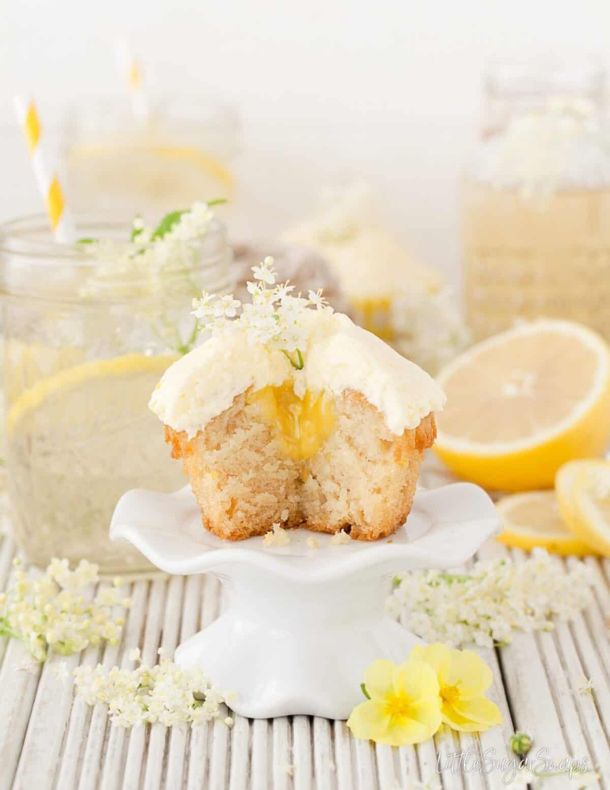 A cut open Vegan cupcake with lemon curd centre and elderflower garnish.