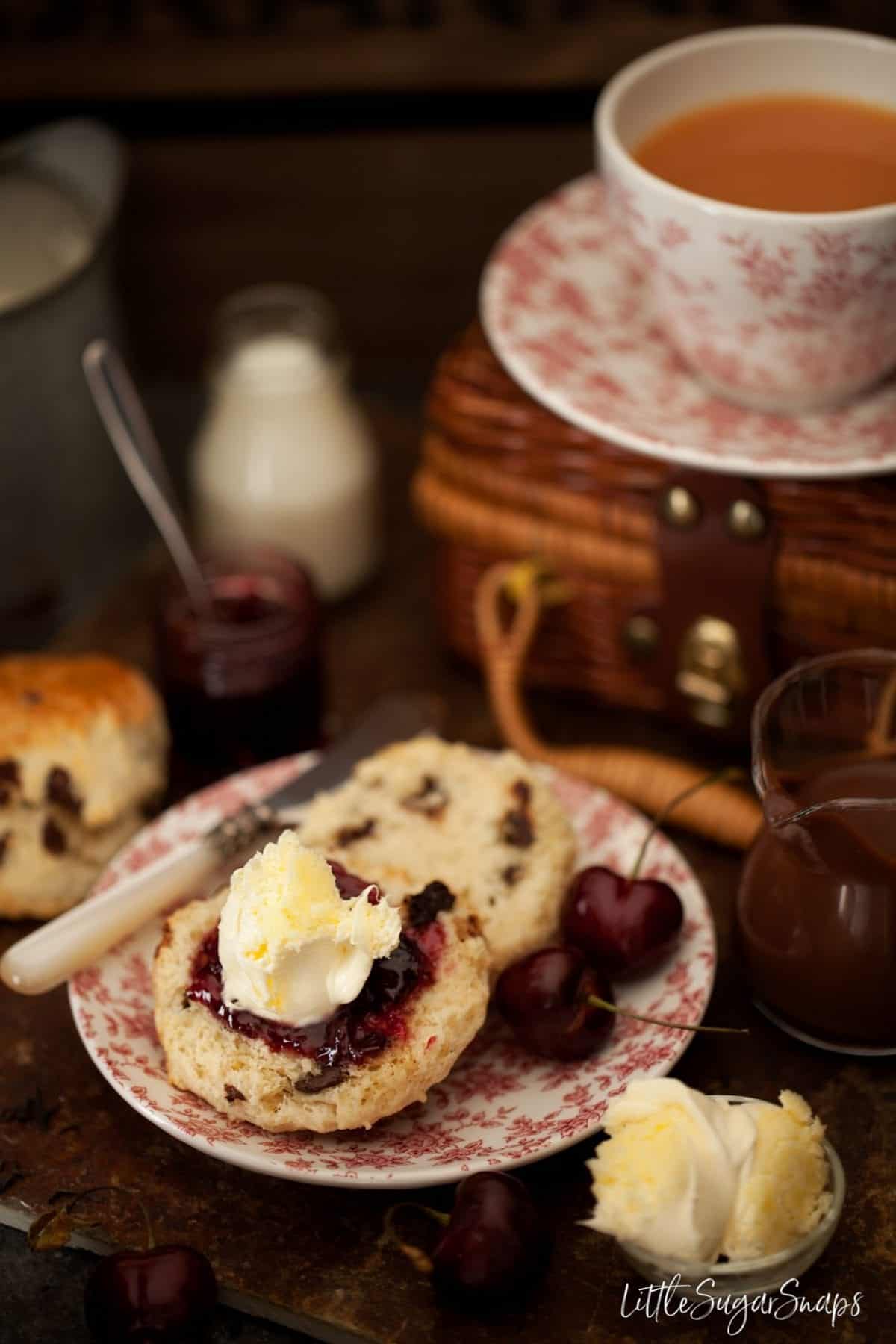 Chocolate chip scone with jam and clotted cream as part of a cream tea.