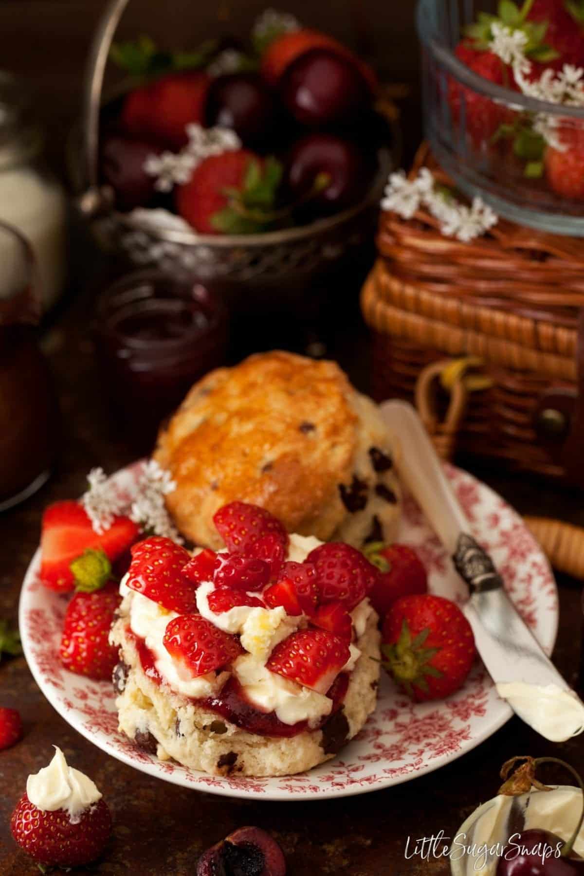 A chocolate chip scone with strawberries, jam and cream.