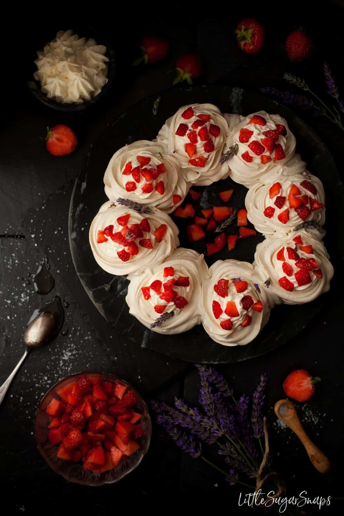 Meringue  pavlova in a wreath shape with strawberries and cream.