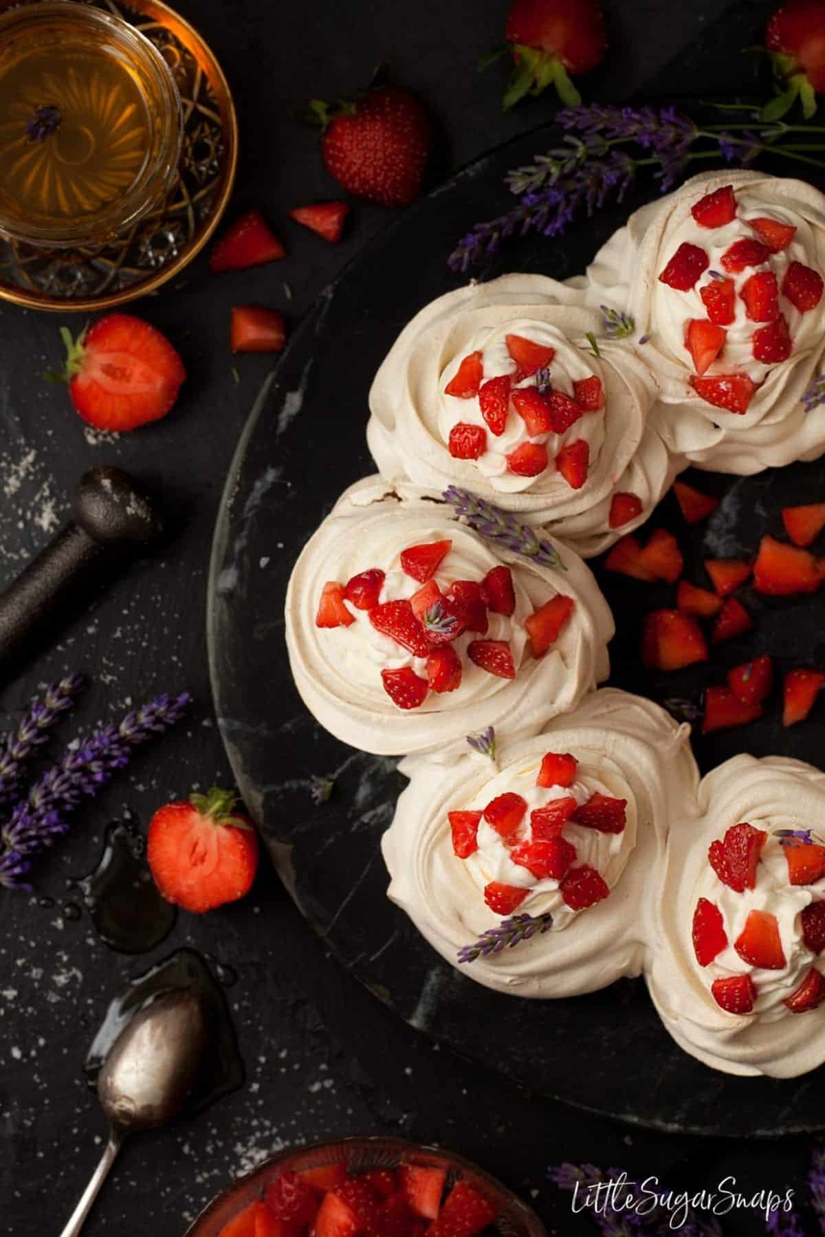 Half circle of meringue nests baked into a wreath shape with strawberries and cream.