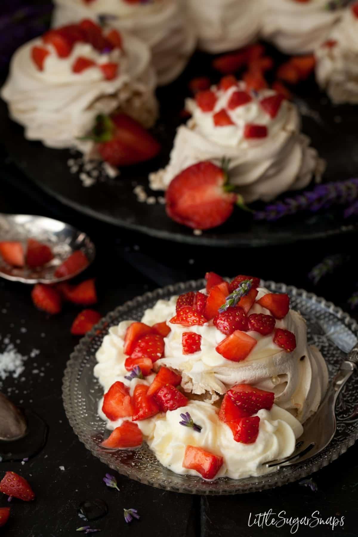 Meringue pavlova on a plate with salted honey cream, strawberries and honey drizzle.