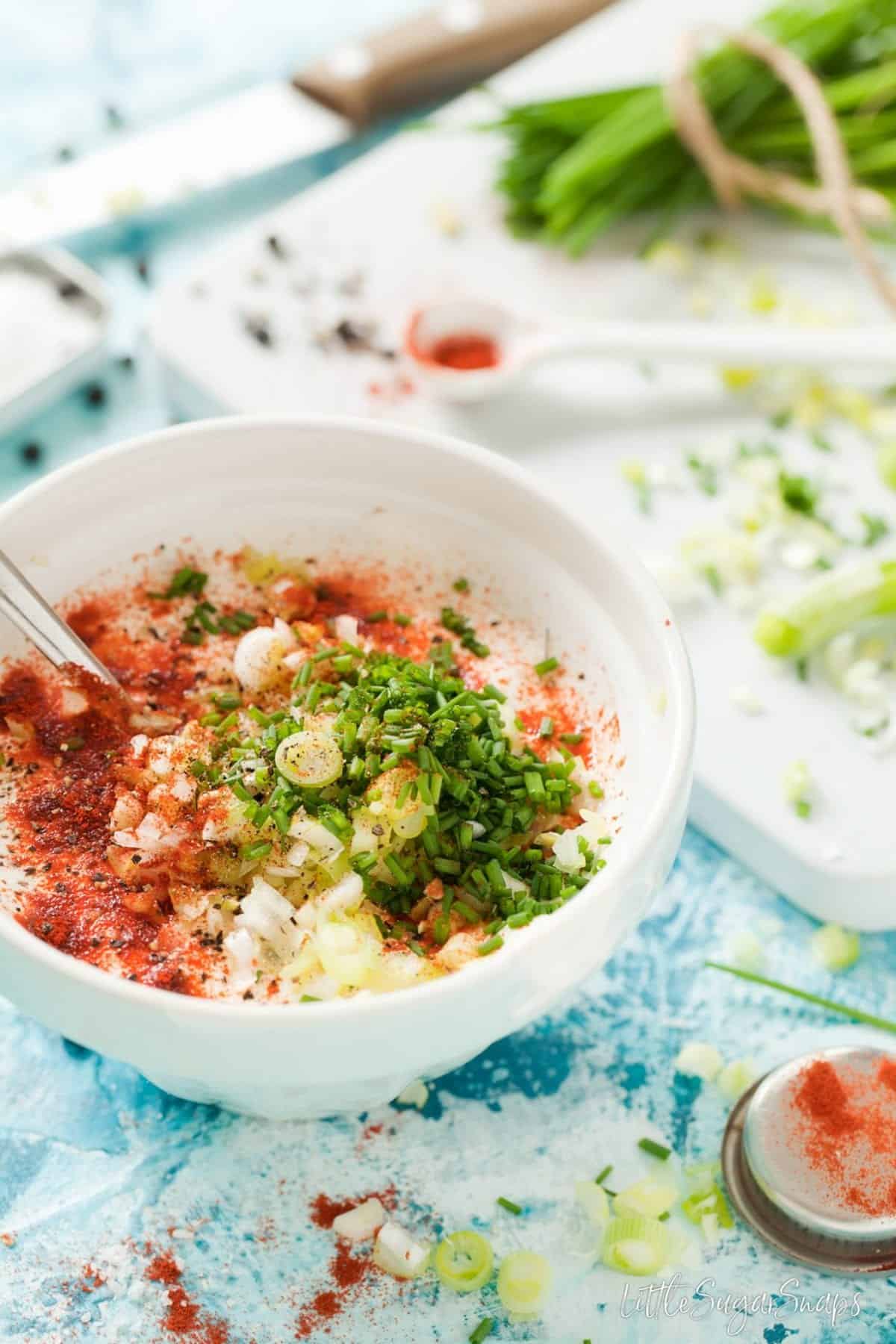 Ingredients in a bowl: soured cream, yoghurt, chives, paprika, spring onion.