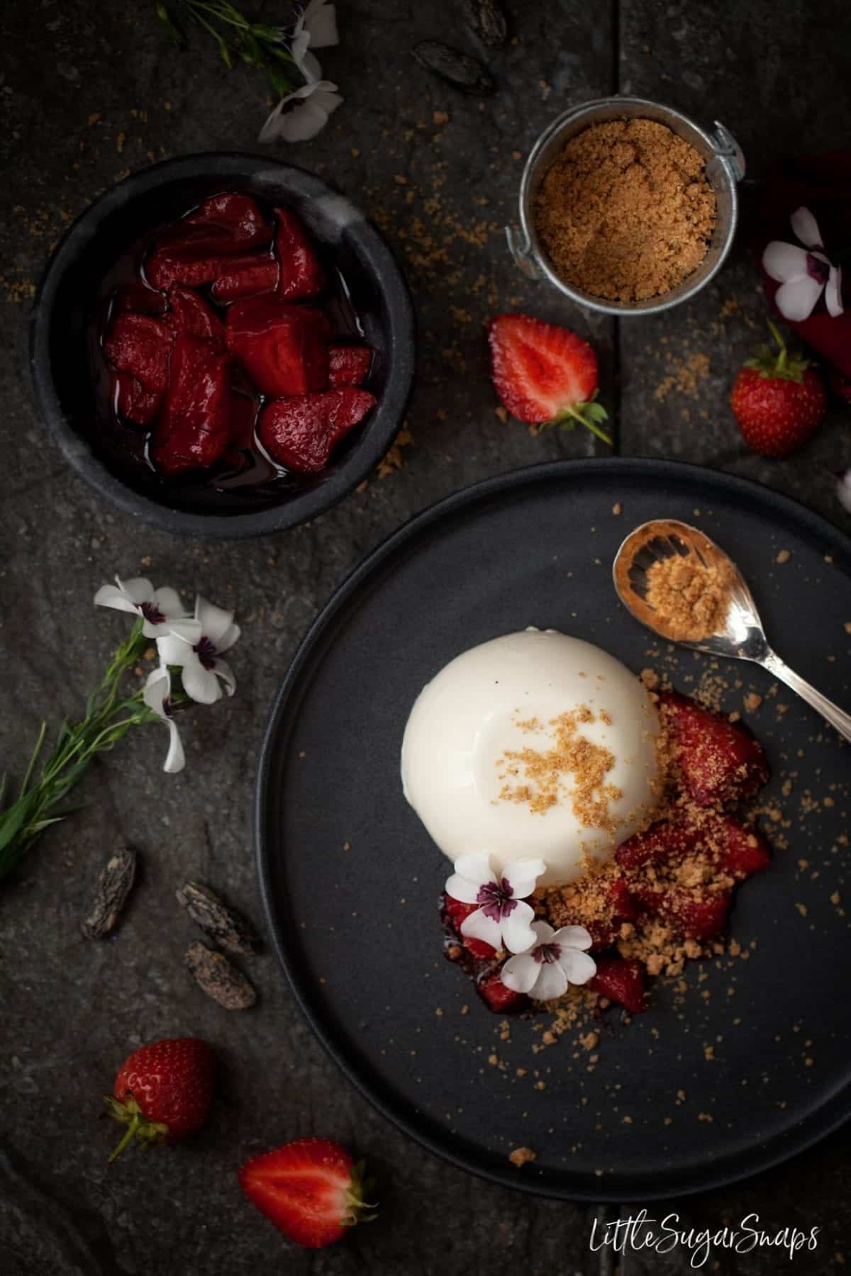 Panna Cotta served with strawberry sauce and crumble pieces.