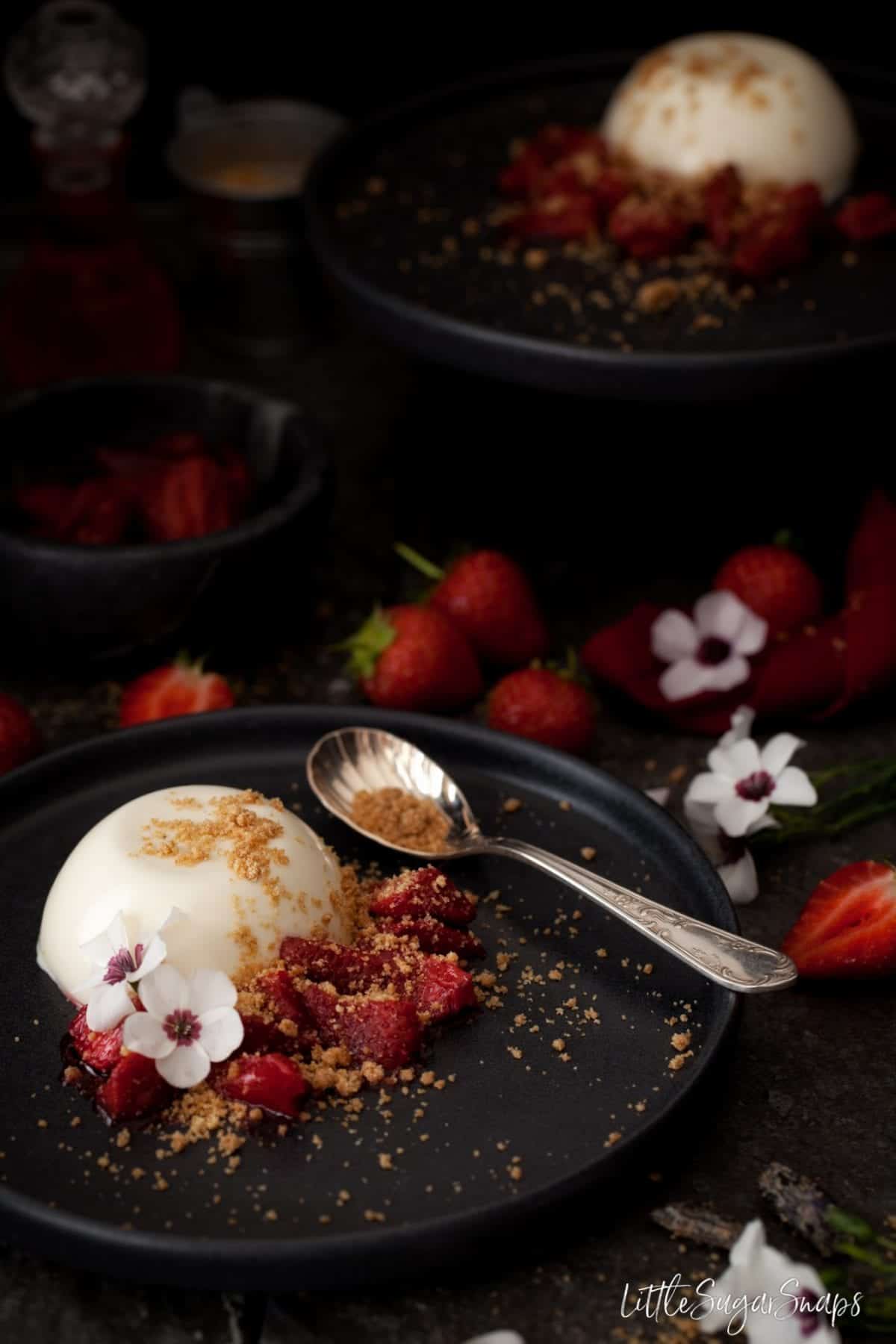 Panna Cotta on a plate with roasted strawberries and crumble topping.