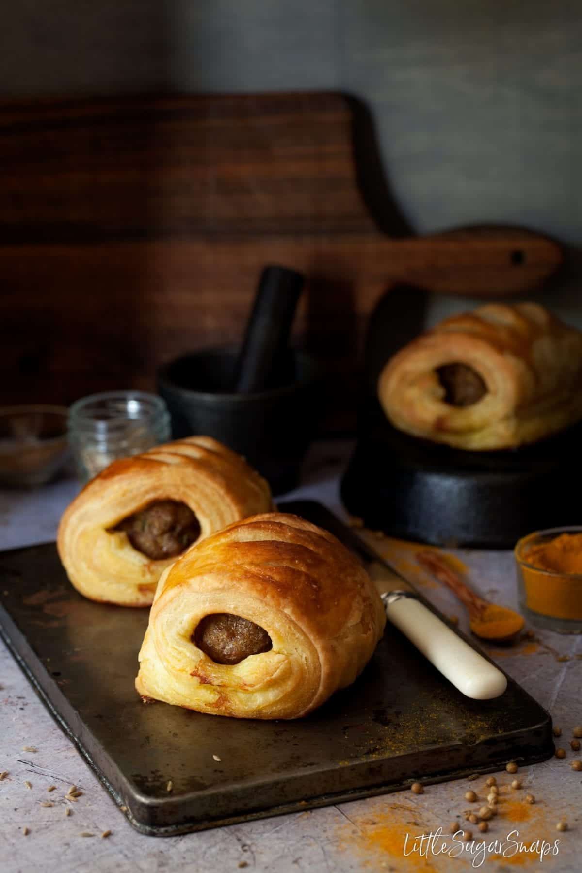 Lamb pastry rolls on a small baking tin.