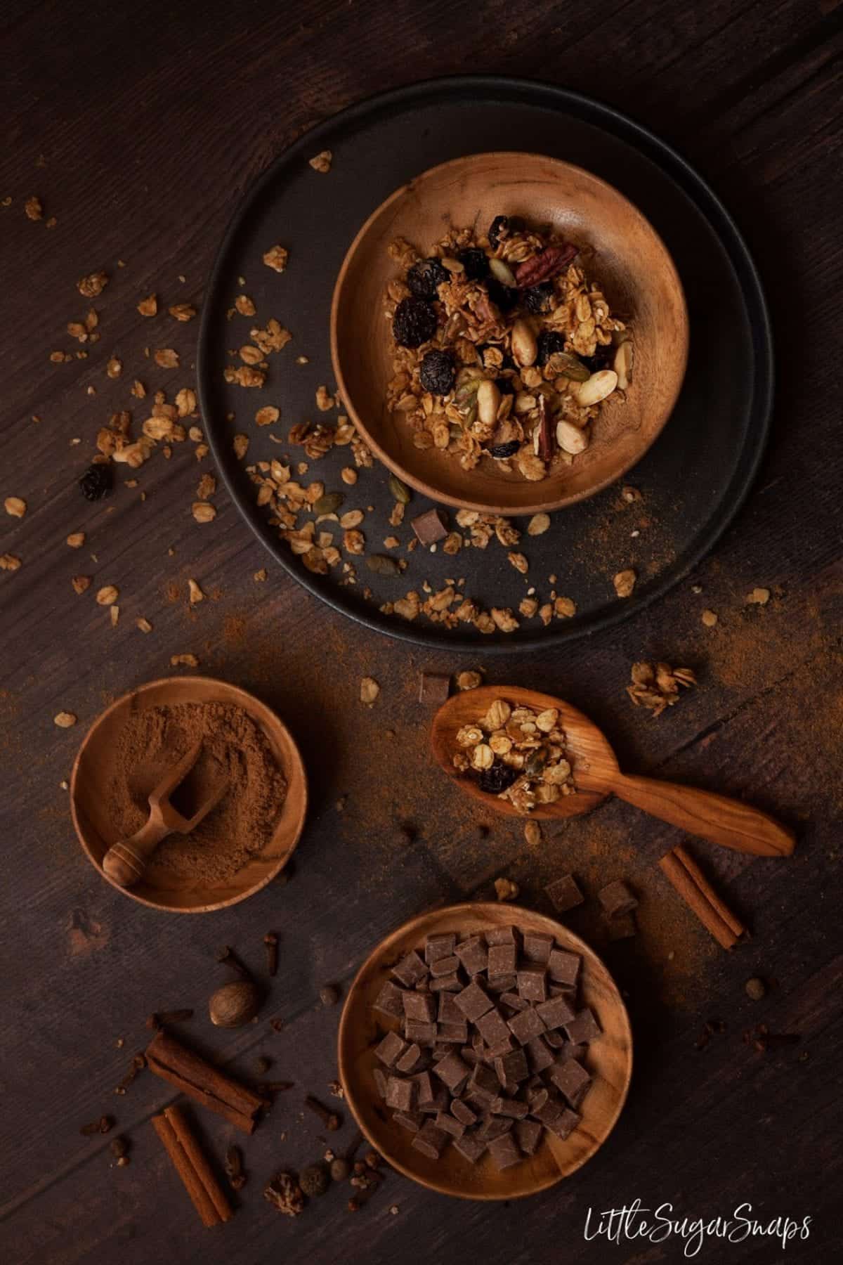 A bowl of granola with chocolate and pumpkin spice alongside.