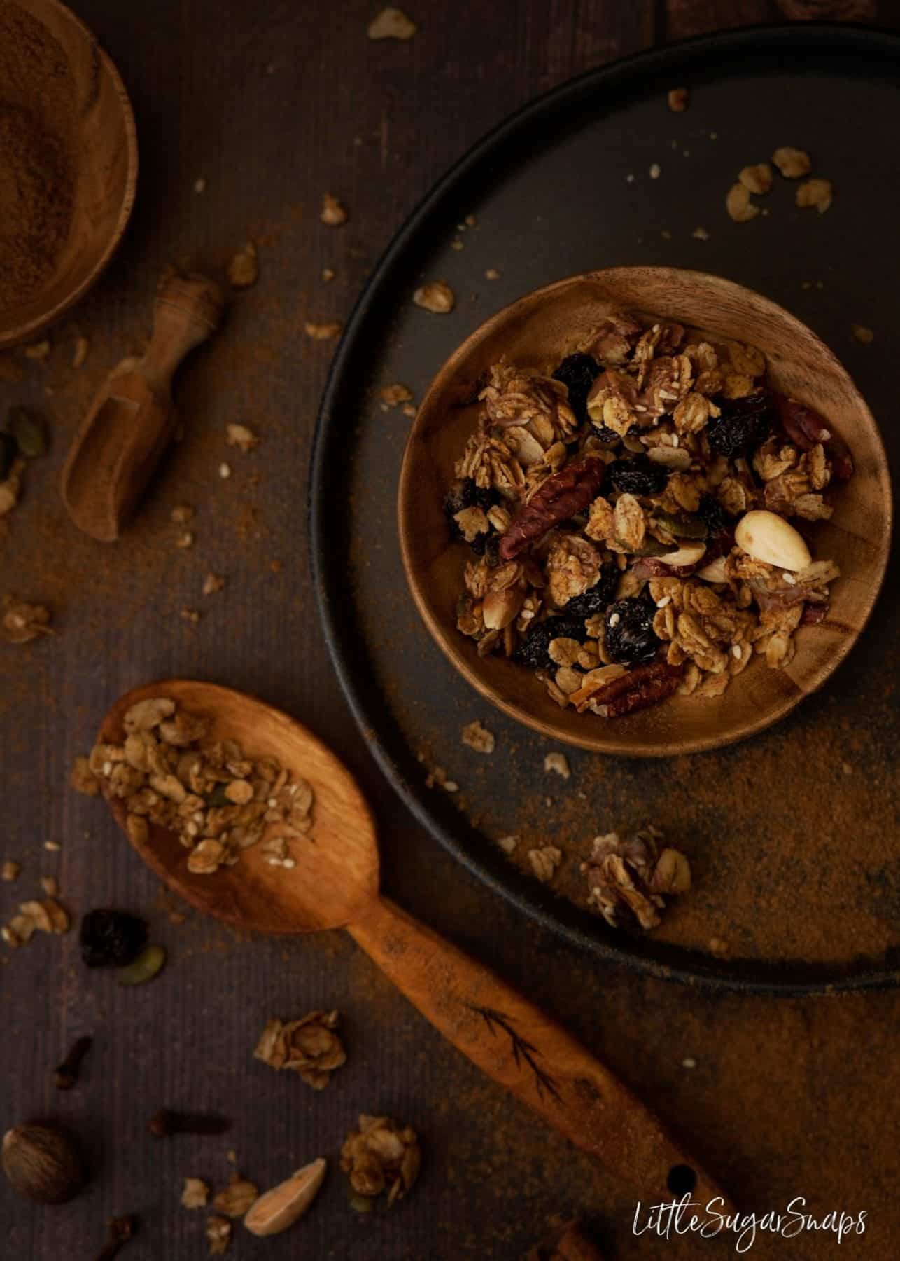 Chocolate Pumpkin Spice Granola in a bowl with a serving spoon alongside.