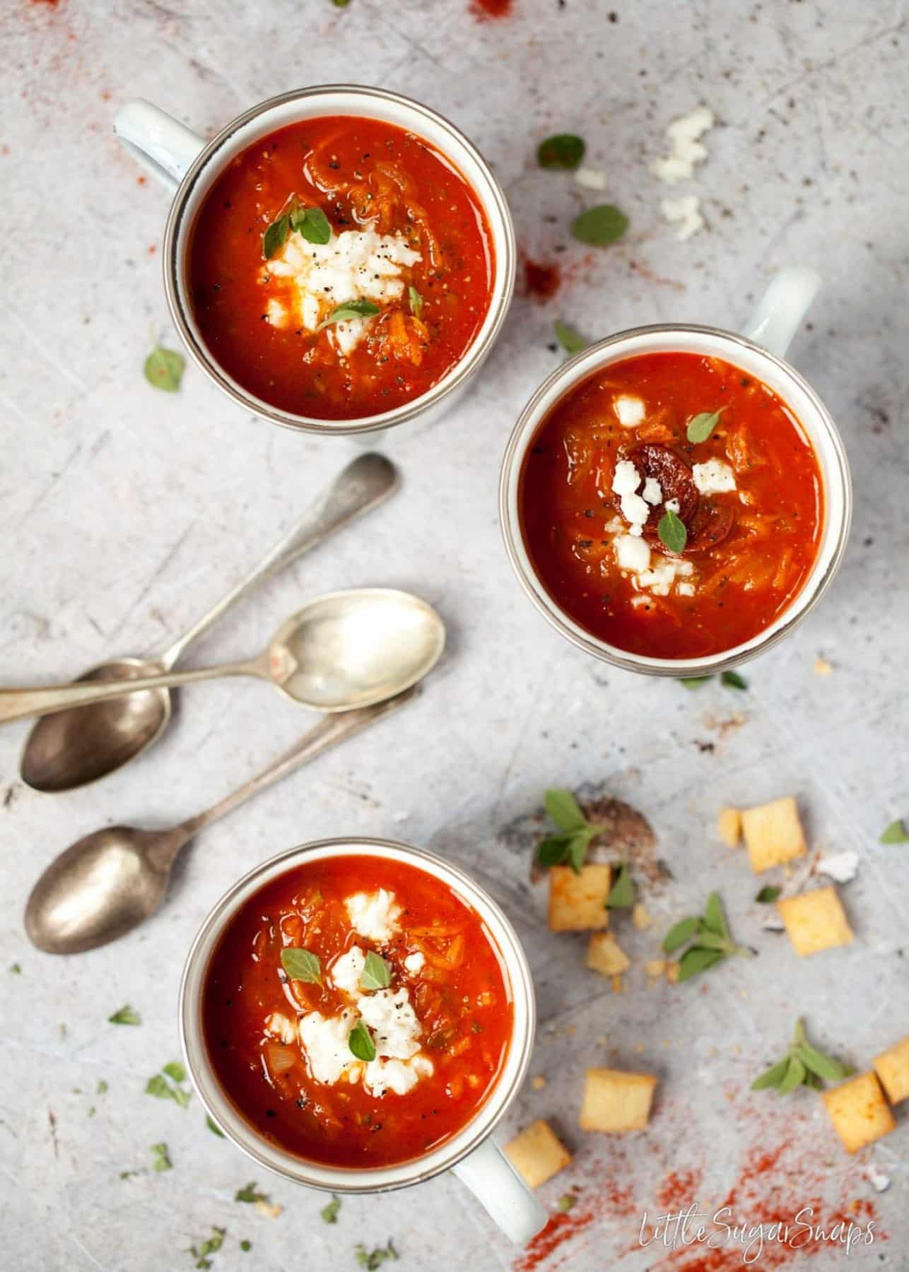 mugs of smoky carrot and courgette soup topped with feta cheese and fresh oregano