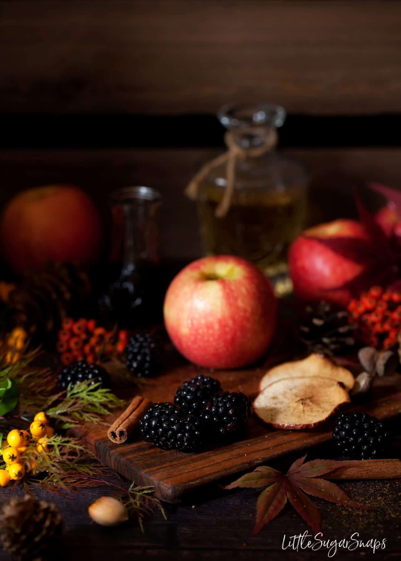 Autumn fruits on a wooden board with seasonal foliage alongside.