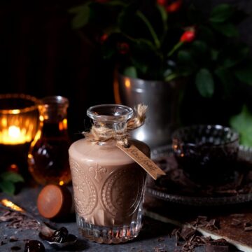 Black Forest Chocolate Liqueur in a bottle with a gifttag. Tealight, fark cherries and grated chocolate surrounding the bottle