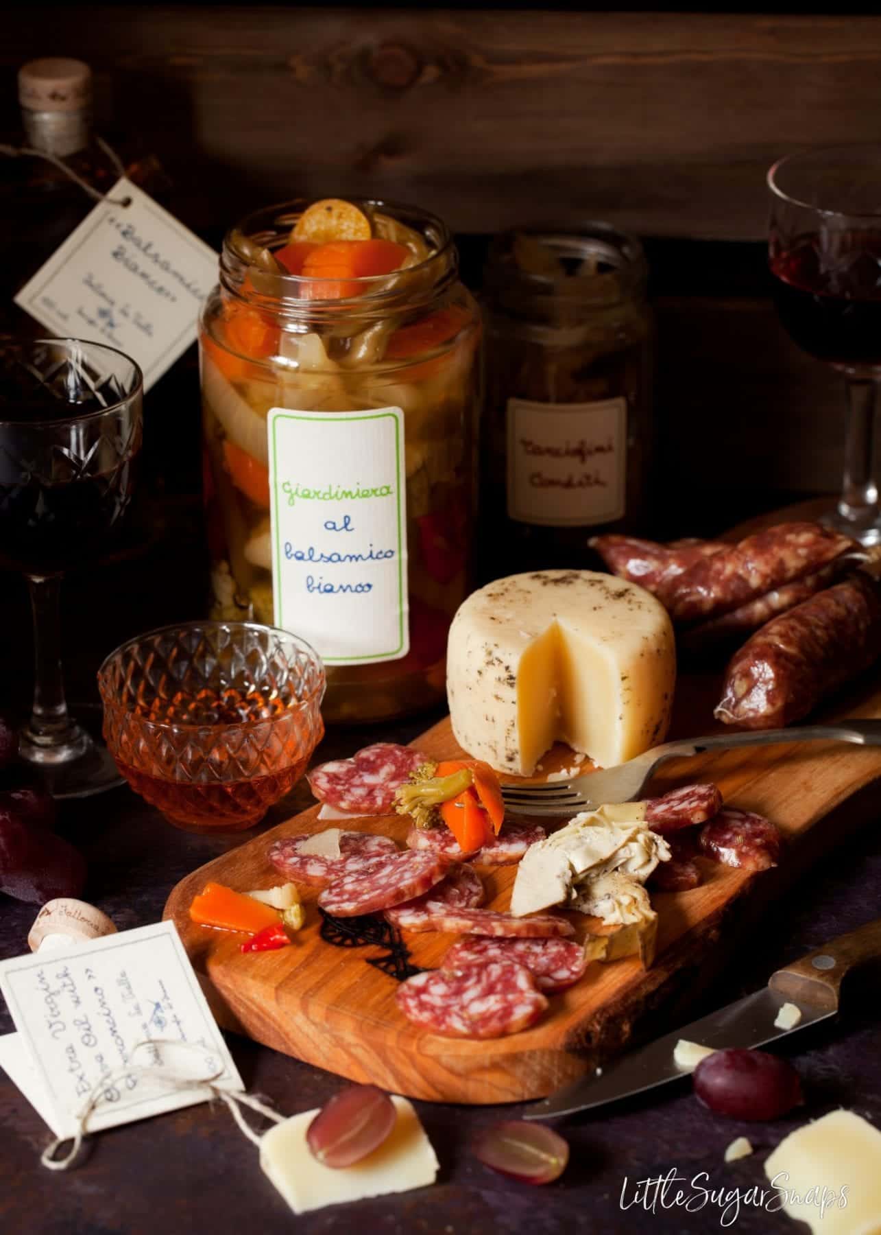 Slices of salami with pickled vegetables and cheese on a wooden board.