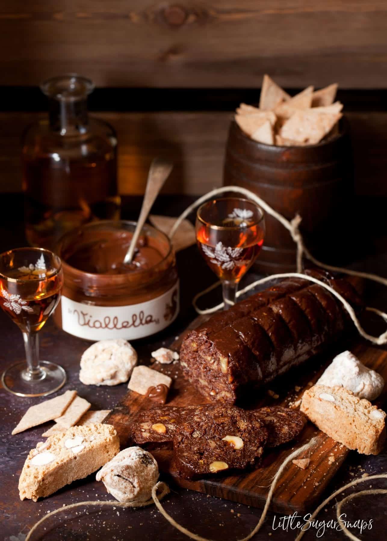 Chocolate salami, chocolate spread and biscuits on a serving board with a glass of vin santo