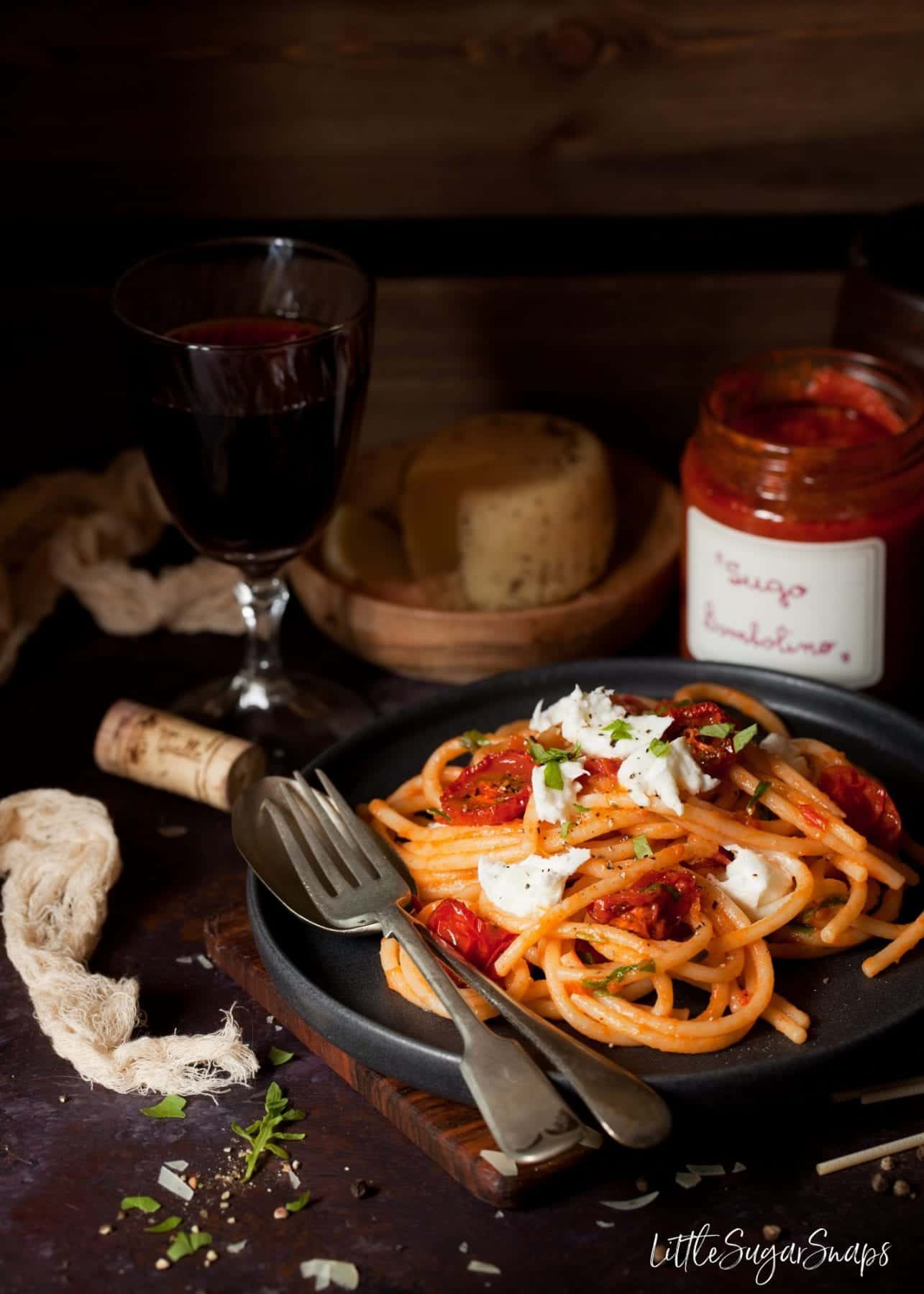 A plate of pasta with roast tomatoes, mozzarella and rocket.