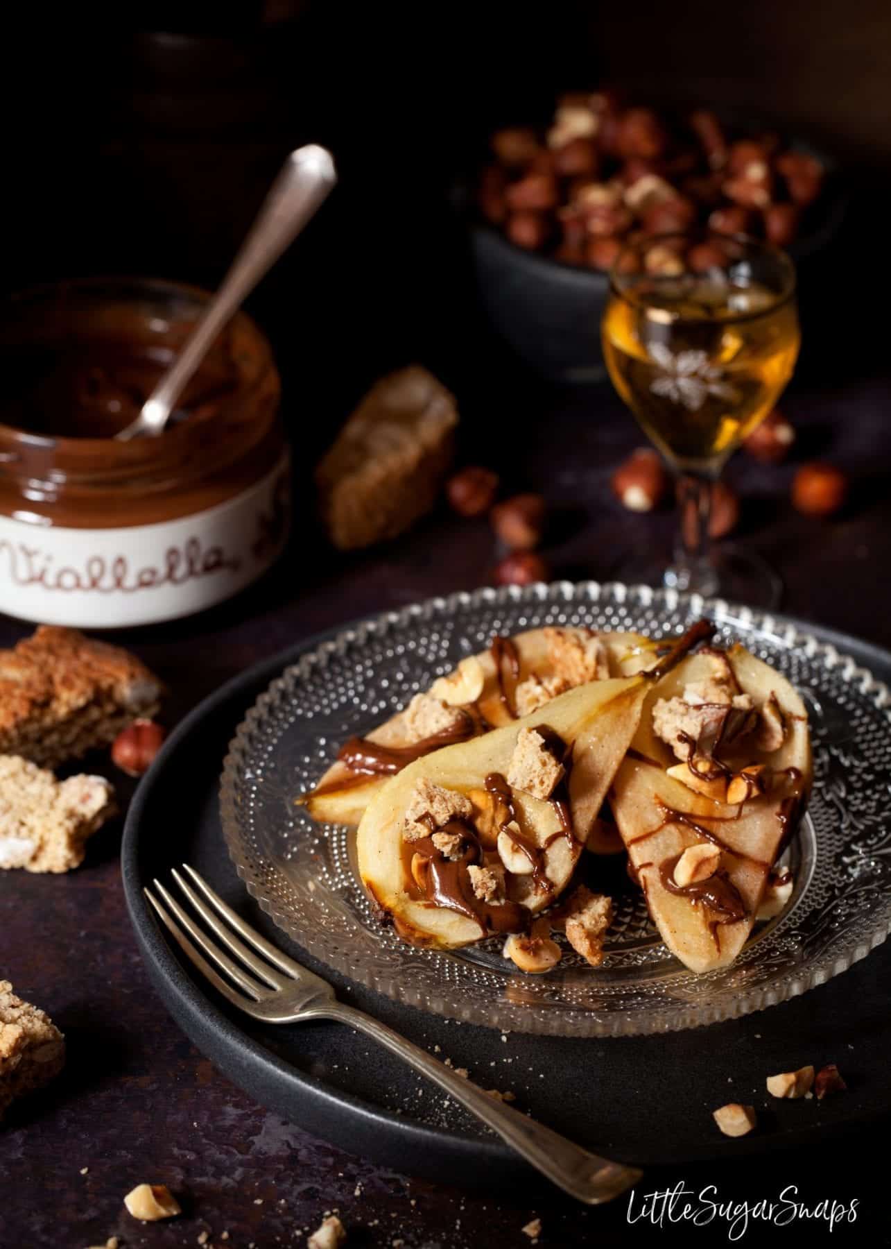 Honey Baked Pears with Chocolate, cantucci biscuits on a plate with a glass of vin santo.