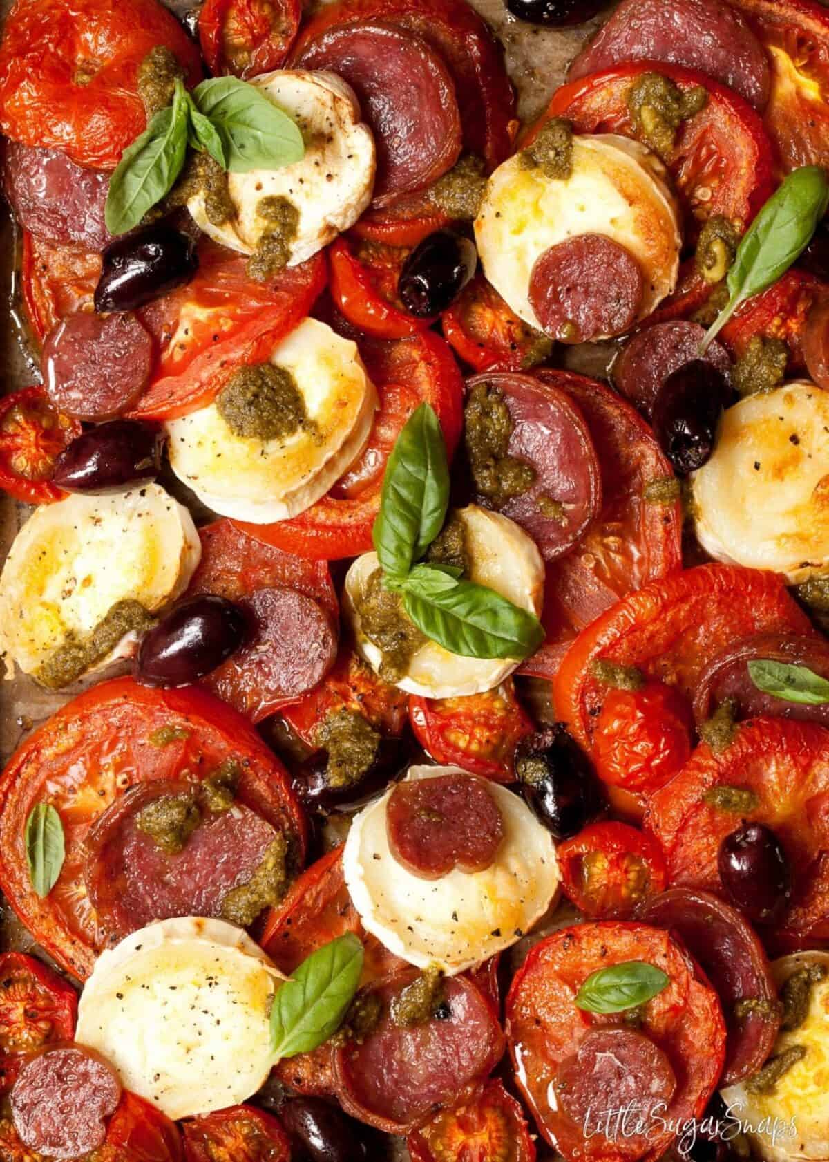 Close up of baked tomatoes, goats cheese, salami and olives. 