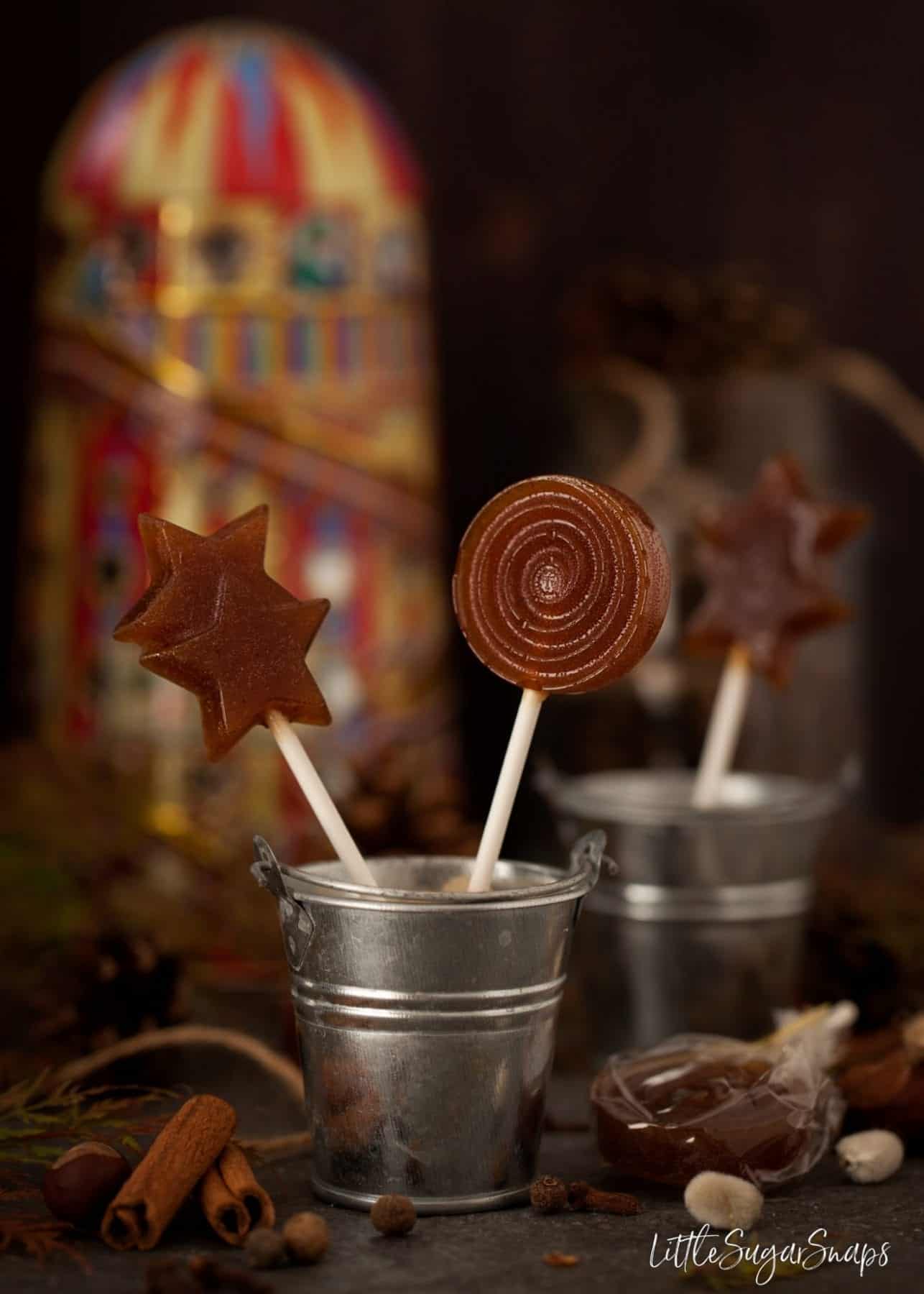 Small metal buckets containing pumpkin spiced toffee lollipops.