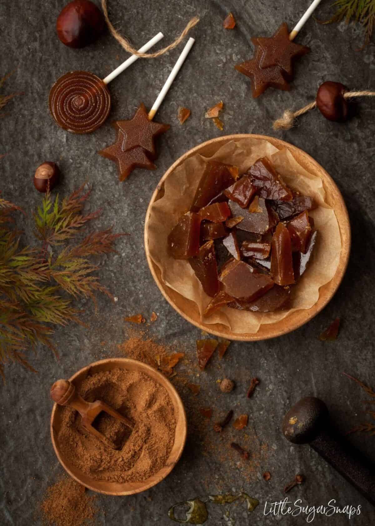 Pumpkin Spiced Toffee pieces in a wooden bowl with lollipops alongside.