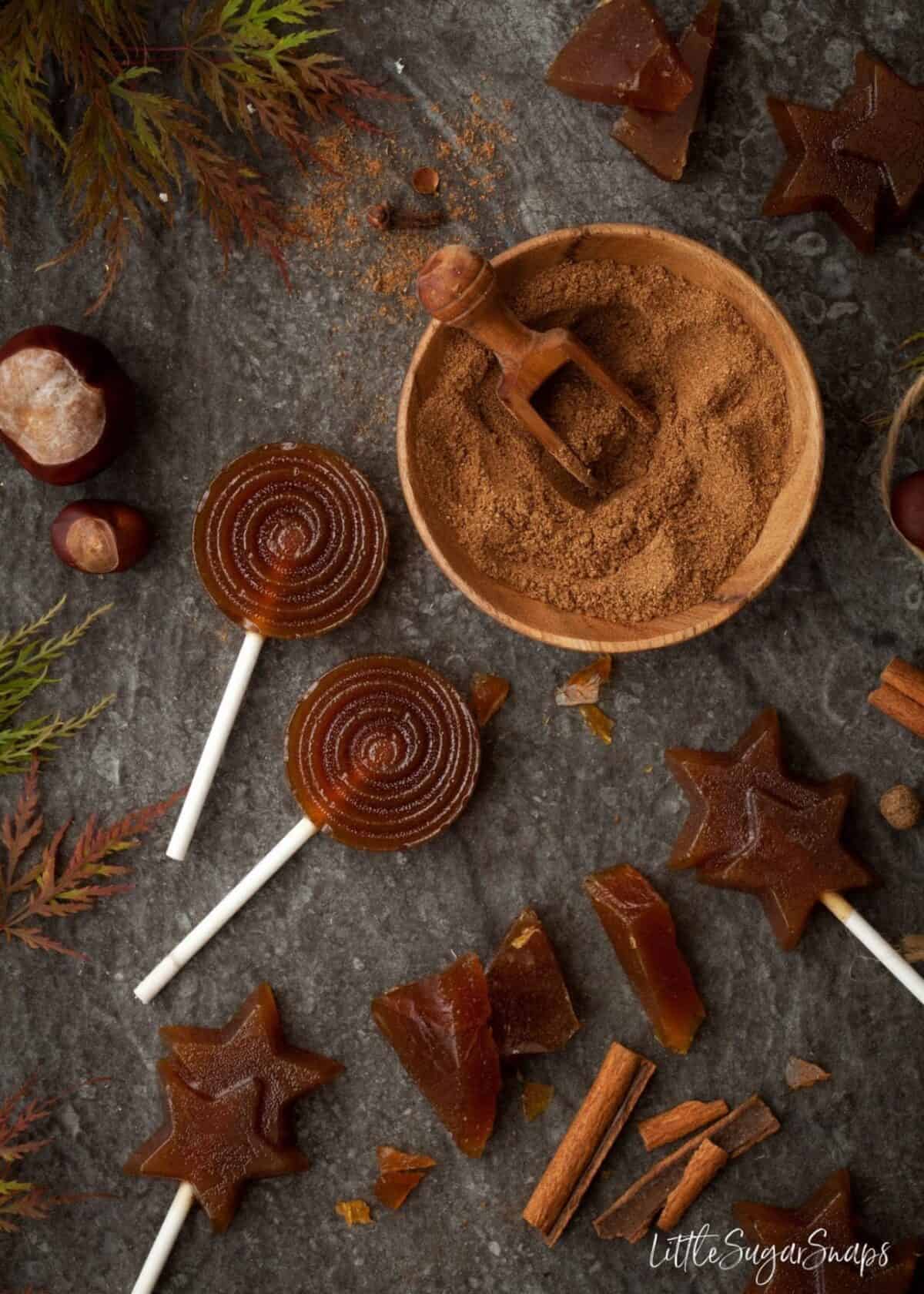 Spiced Toffee pieces and toffee lollipops on a grey worktop.