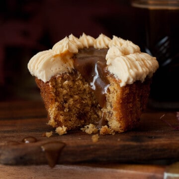 A bitten into sticky toffee cupcake with toffee sauce dripping into the centre of the cake.