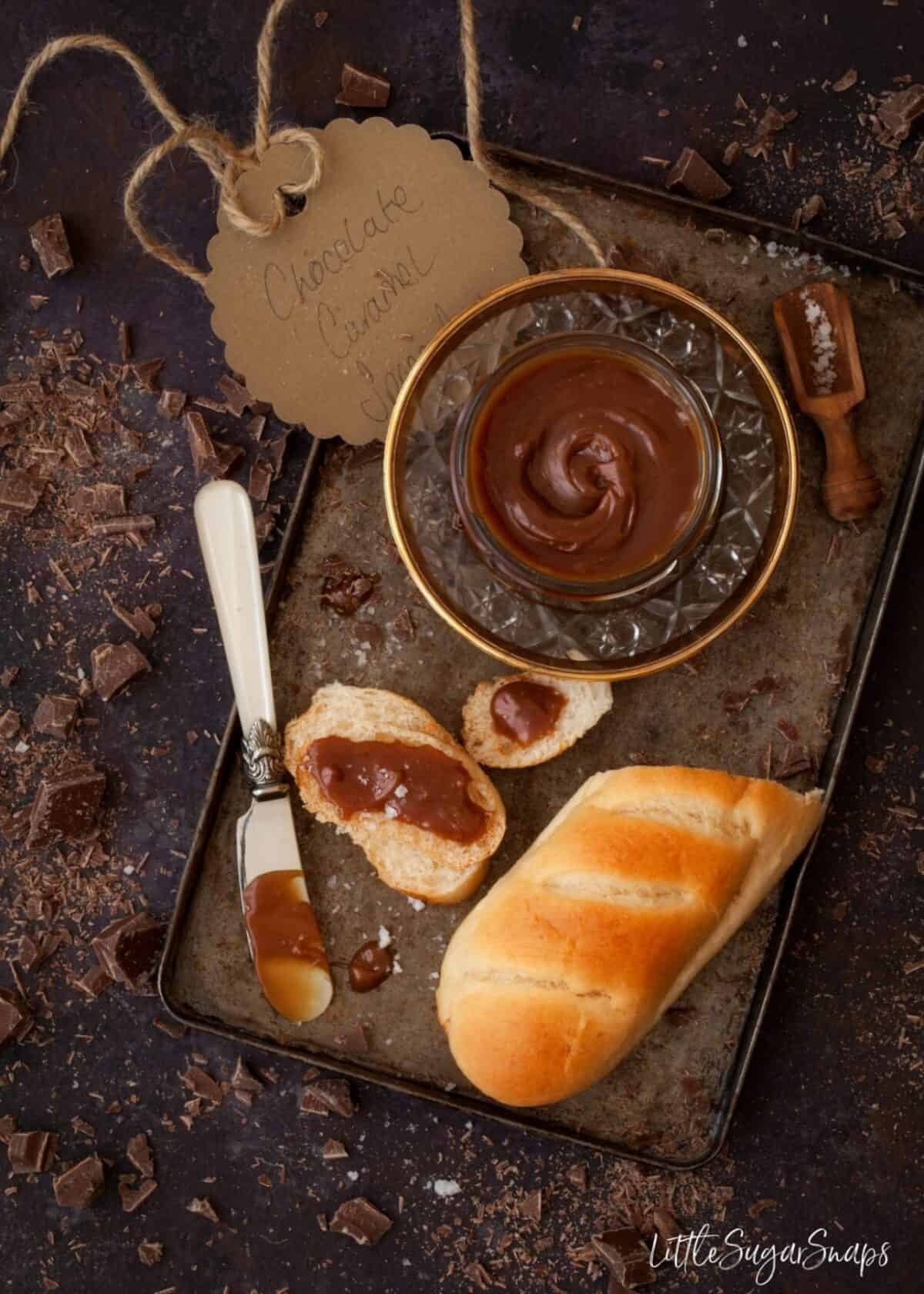 Chocolate Caramel Spread being spread on a small brioche roll.