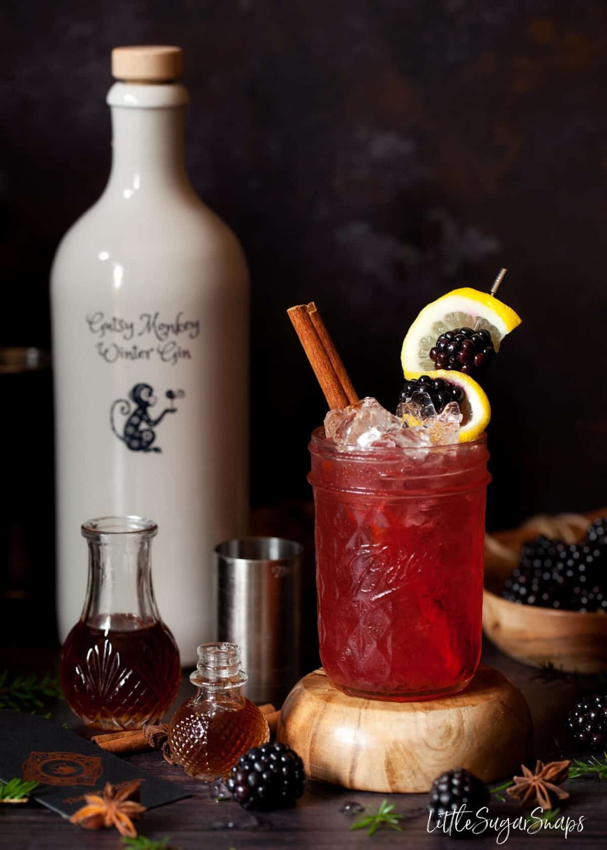 A blackberry bramble cocktail made from a recipe including cinnamon syrup (shown alongside).