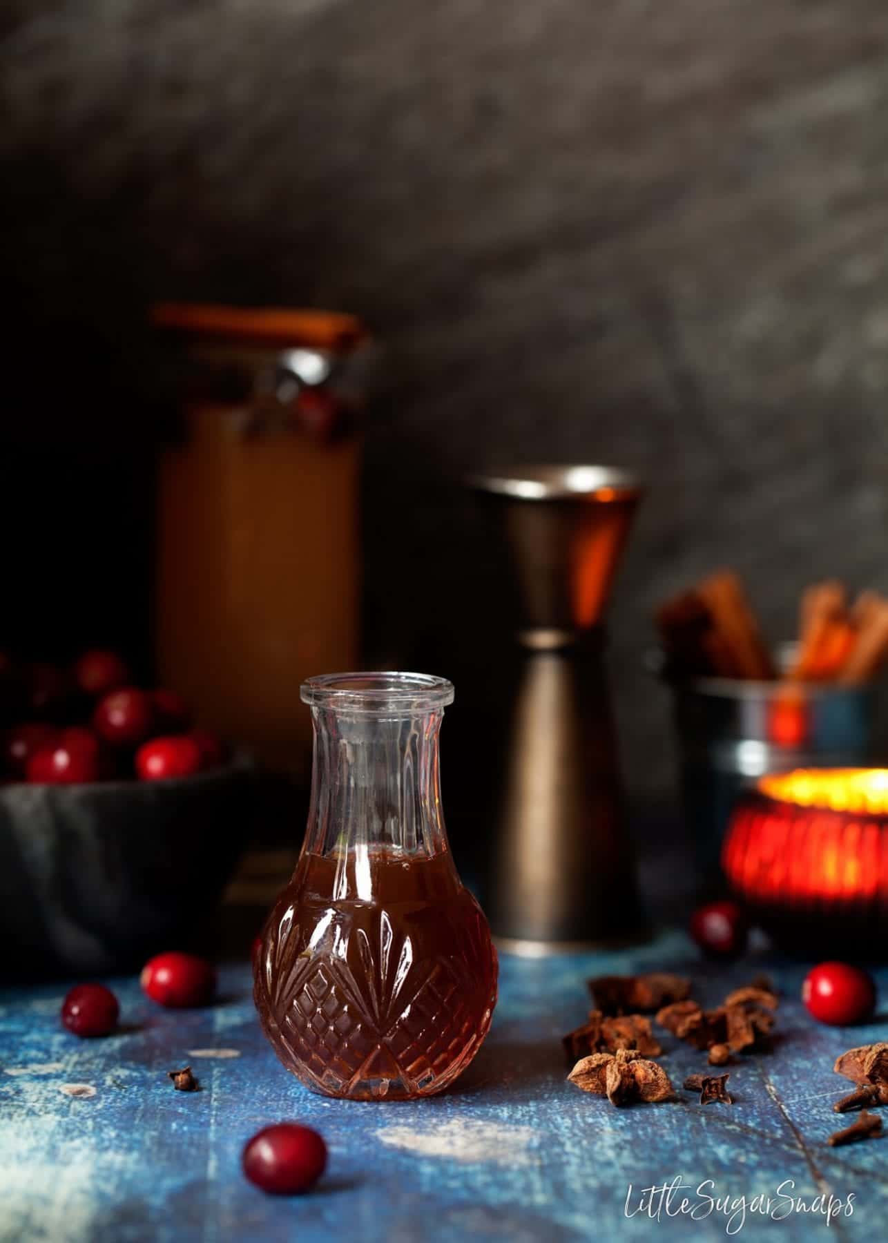 A small bottle of tonic syrup with cranberries, star anise and a tea light