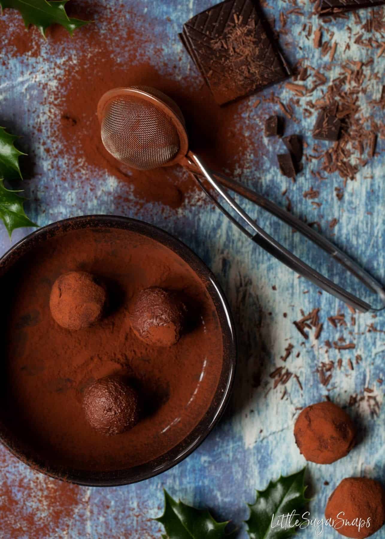 Gin and tonic truffles being dusted in cocoa powder.