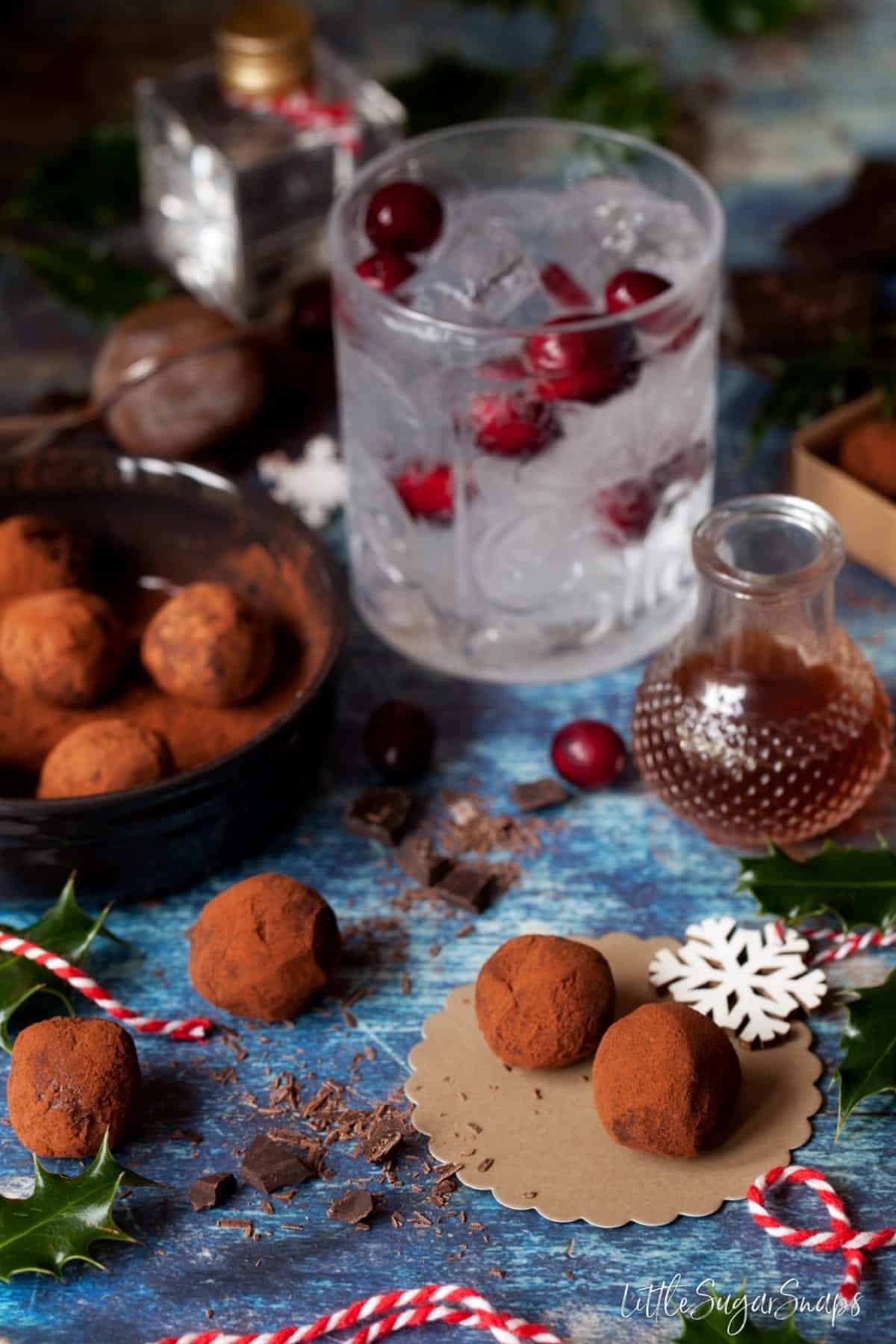 An alcoholic drink with cranberries in it with homemade chocolate alongside.