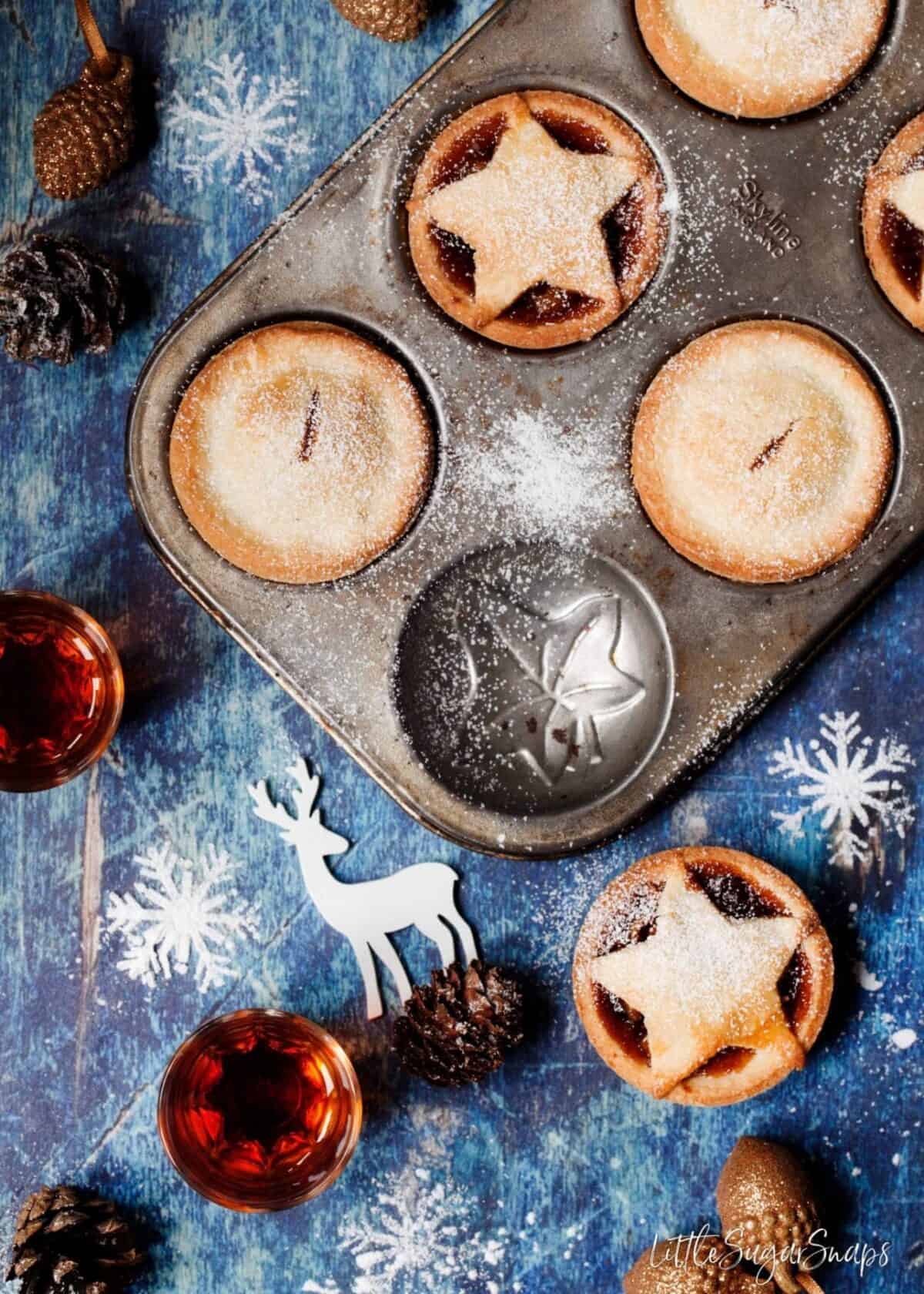 Gluten Free Mince Pies freshly baked in the tin with pine cones and amaretto