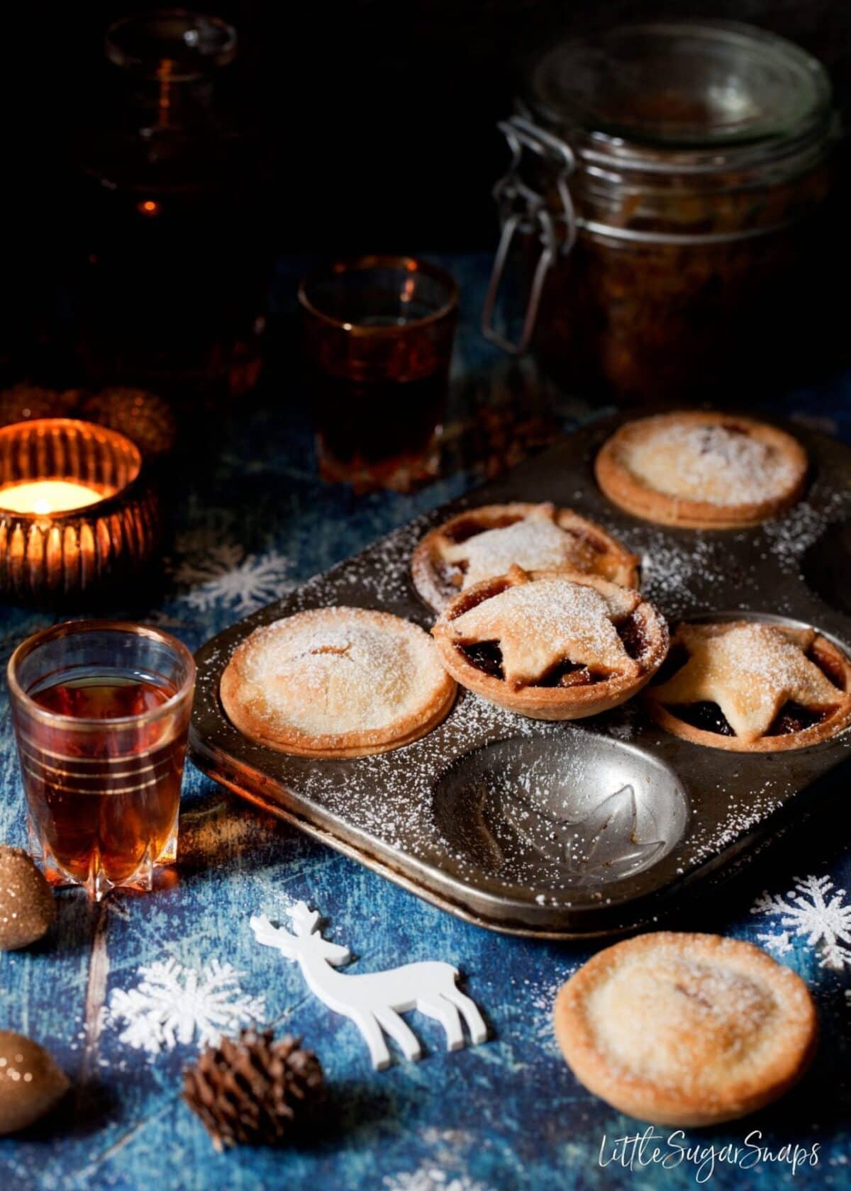 Gluten Free Mince Pies in a vintage baking tin with christmas ornaments and a glass of amaretto