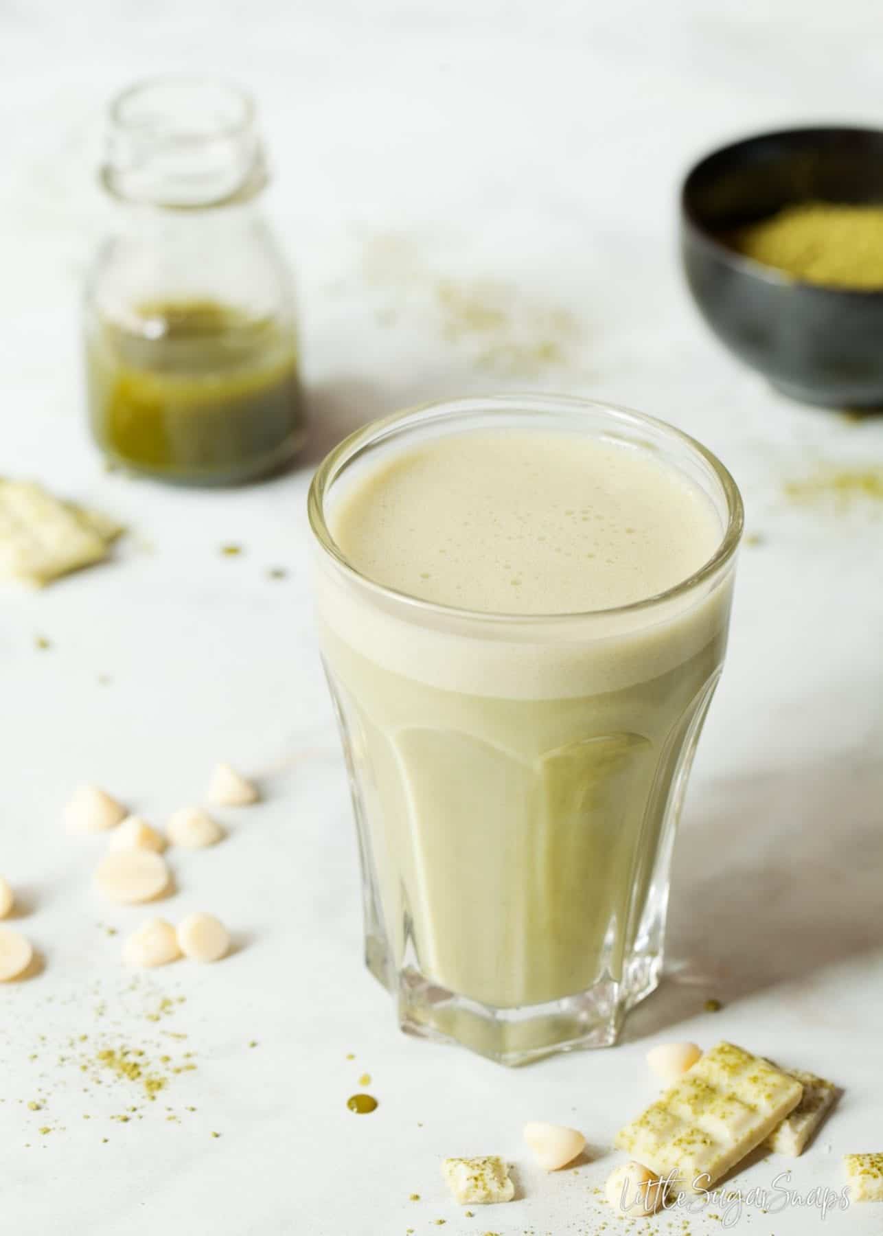 Green coconut chocolate matcha latte in a glass mug with a frothy top