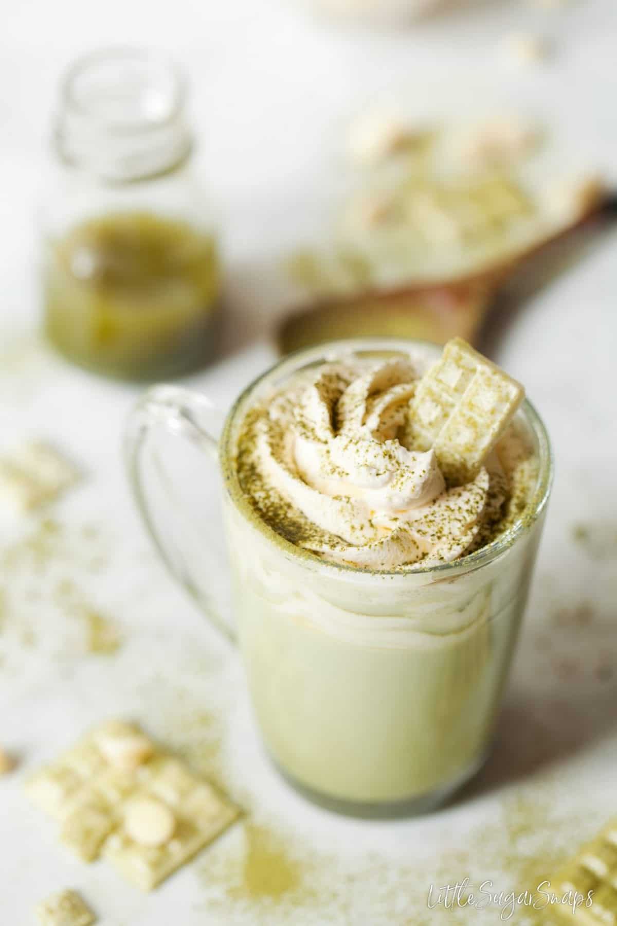 Chocolate matcha latte with whipped cream, matcha powder and a piece of white chocolate