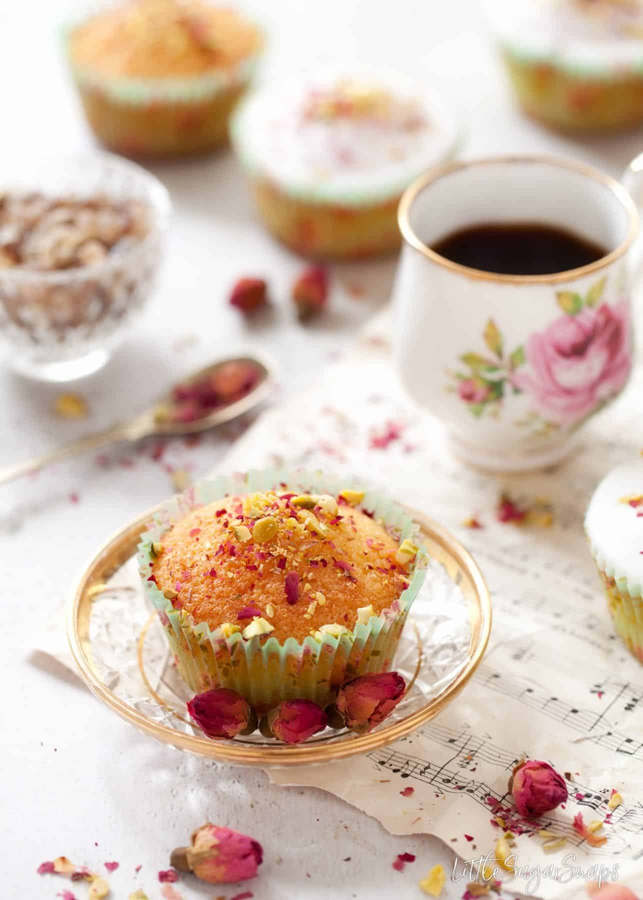 Persian Love Cupcake on a glass plate with a small coffee.