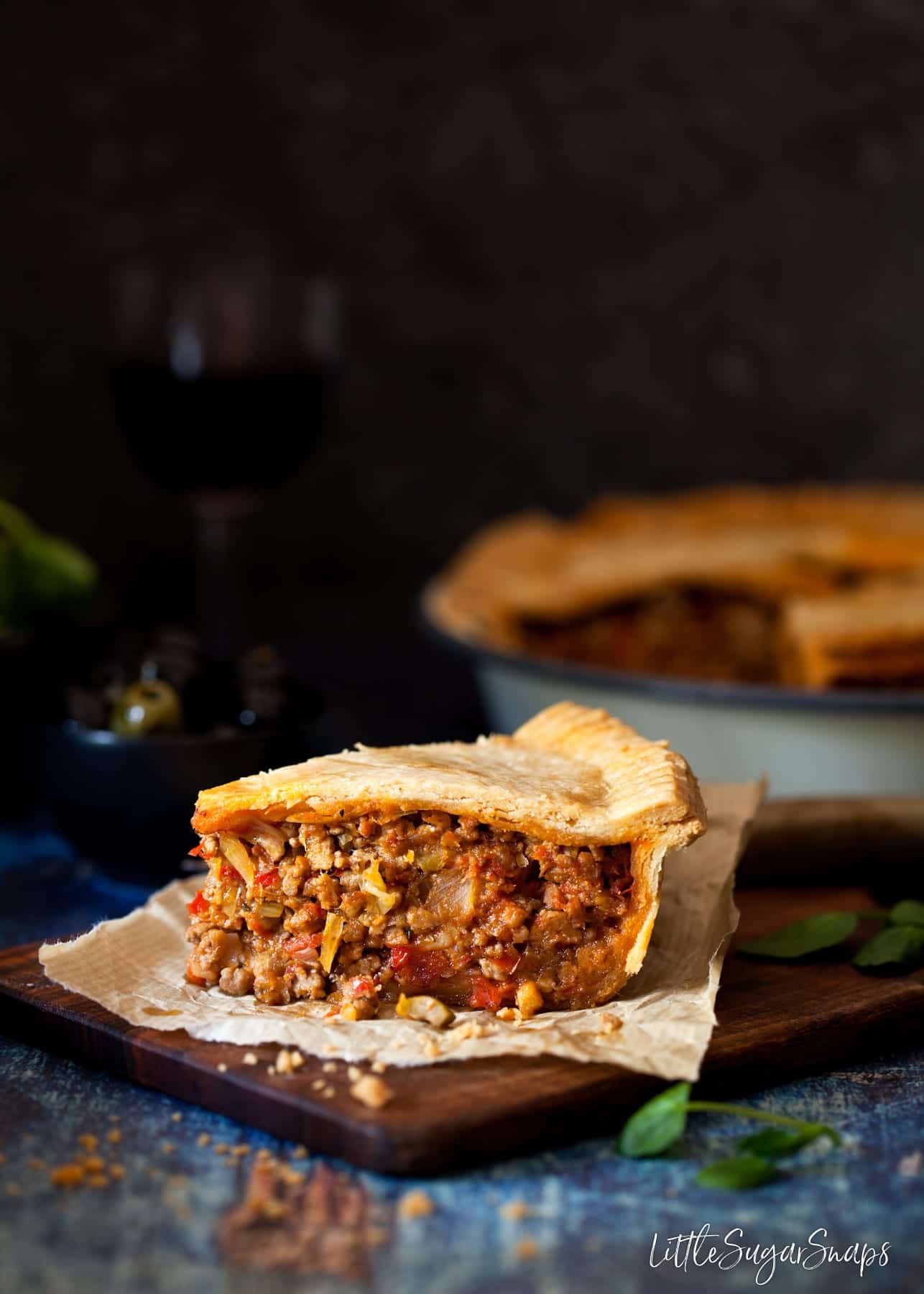 A slice of Mediterranean Lamb Pie on a wooden board.